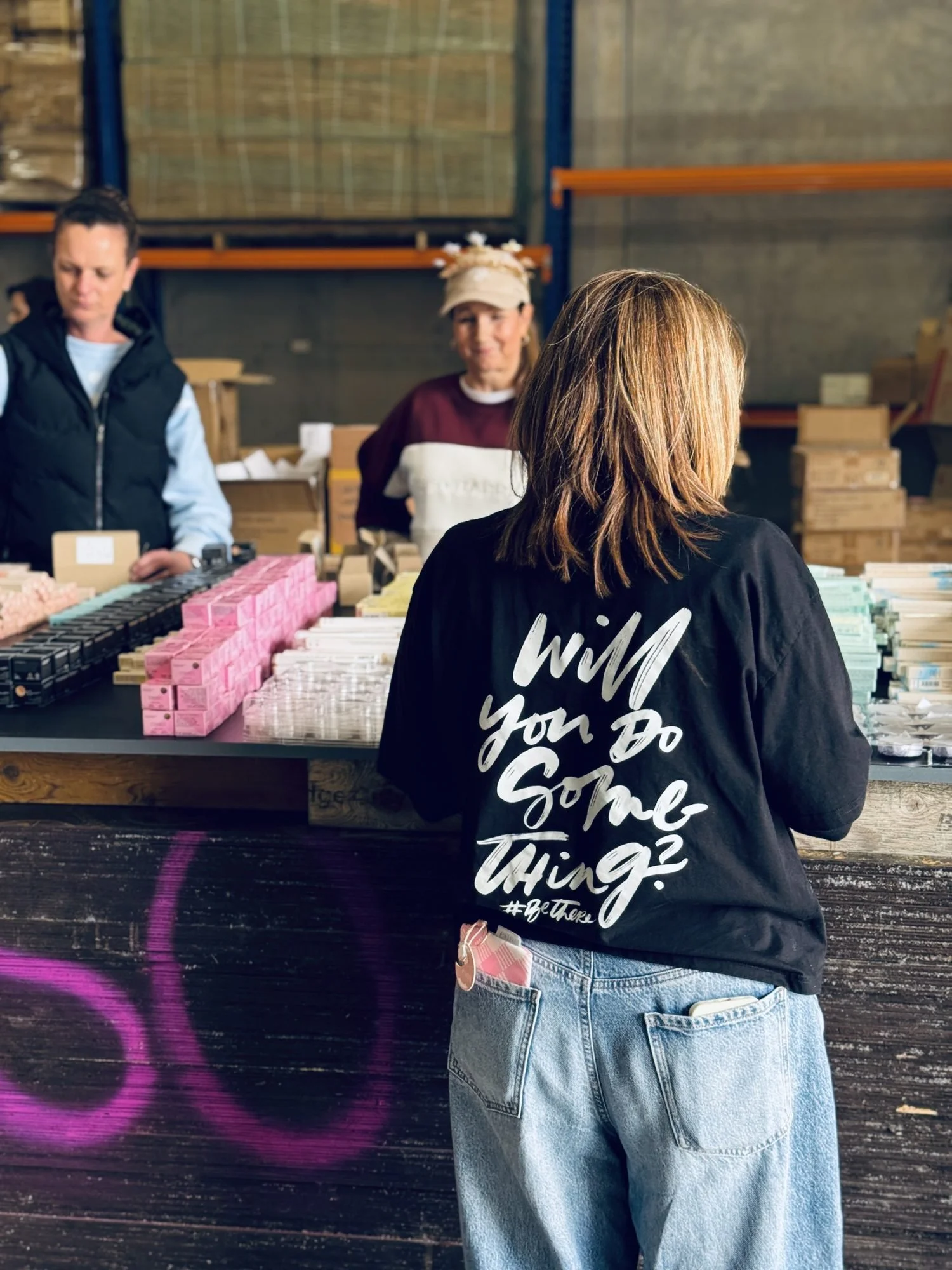 A volunteer in a 'Will you do something?' hoodie working at the packing tables