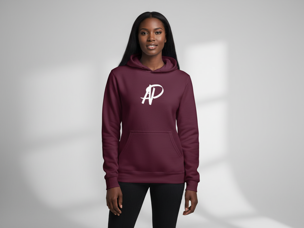 A woman wearing a maroon hoodie with a white stylized 'AP' logo on the front, standing in front of a plain light gray background.