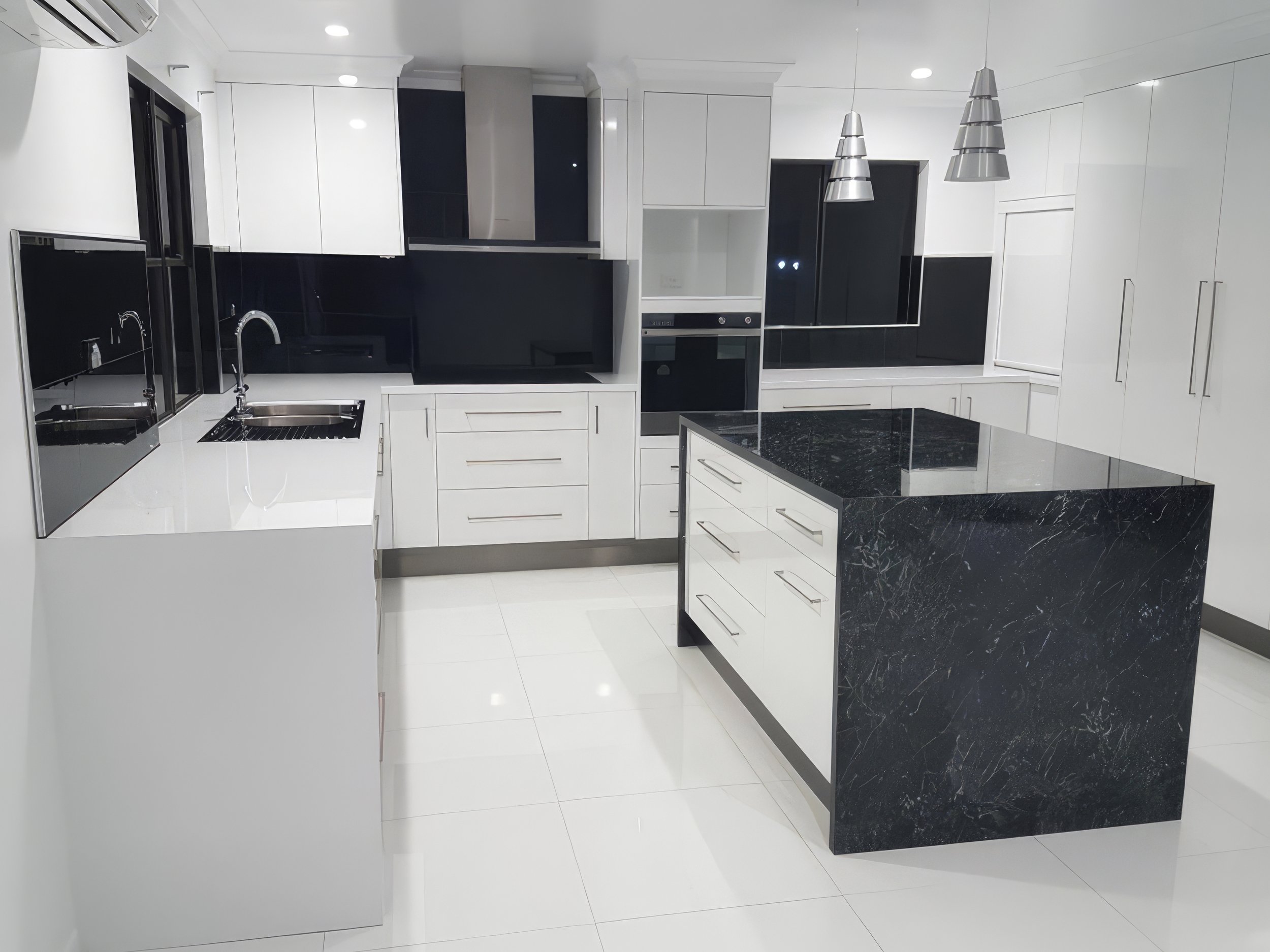 Modern white and black kitchen with island, black countertops, and pendant lighting.