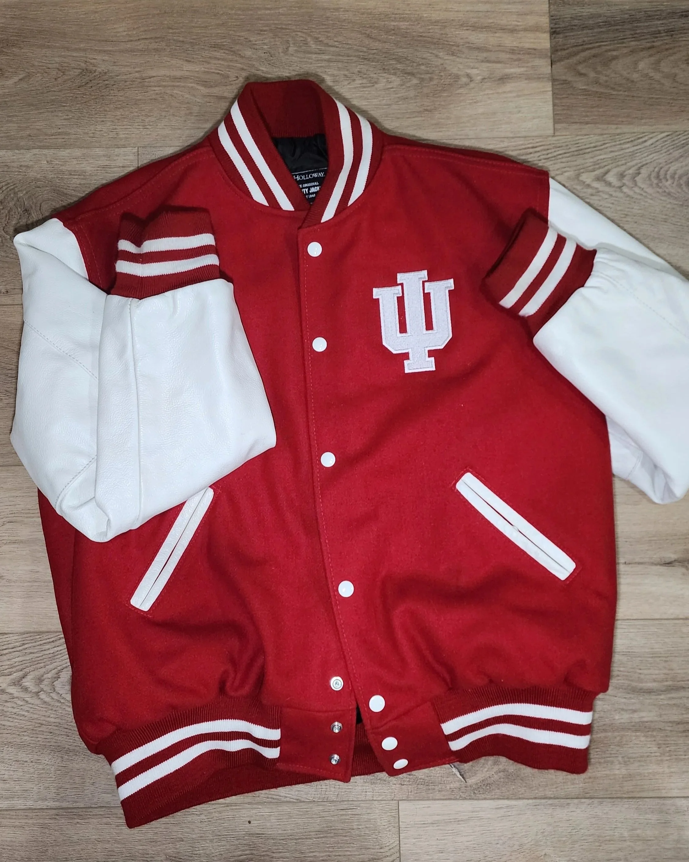red and white varsity jacket with embroidered logo on a left chest