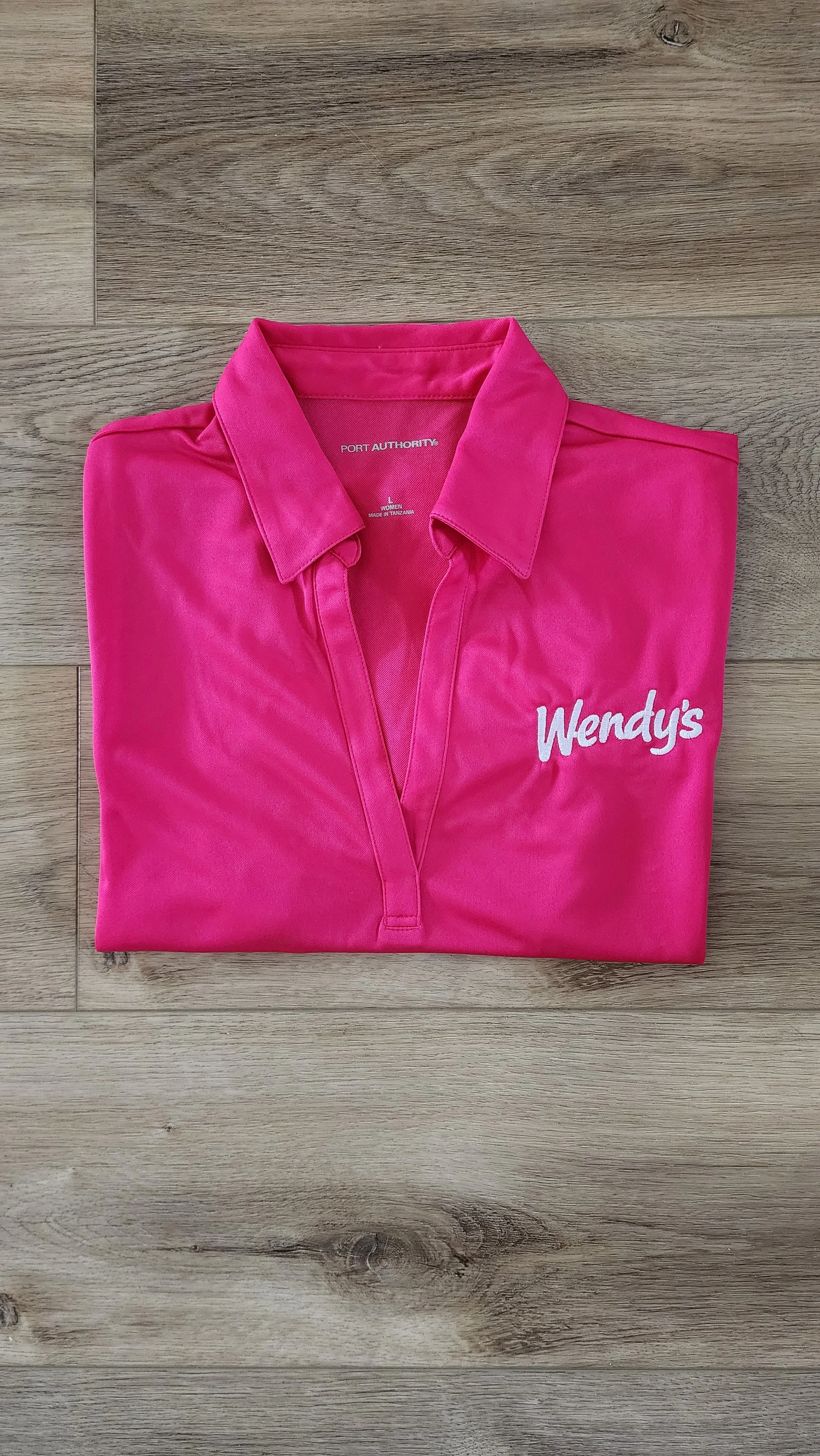 Pink Wendy's uniform polo shirt folded with Wendy's logo visible on the chest.