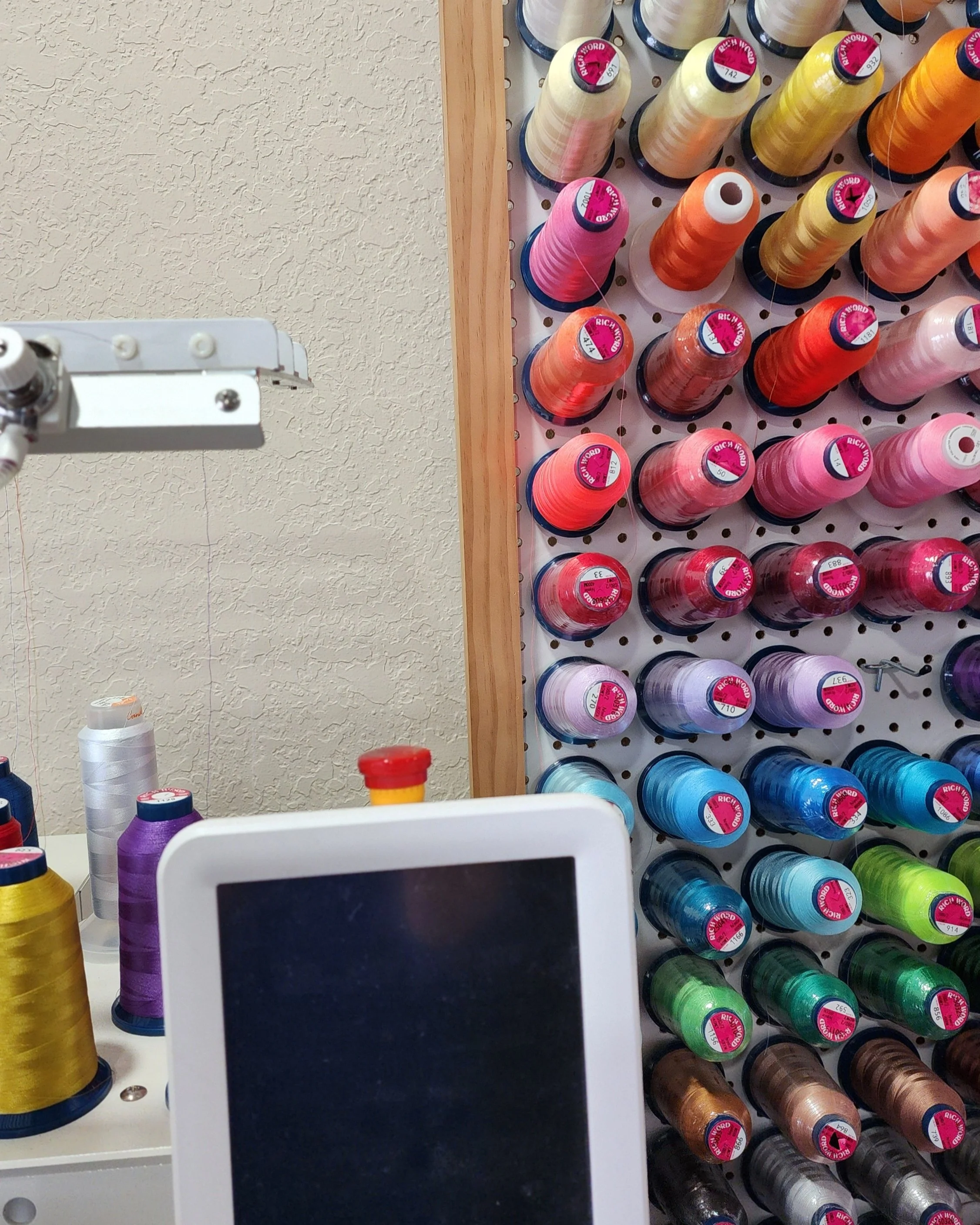 A display of colorful spools of thread arranged on a wall in a sewing or craft store.