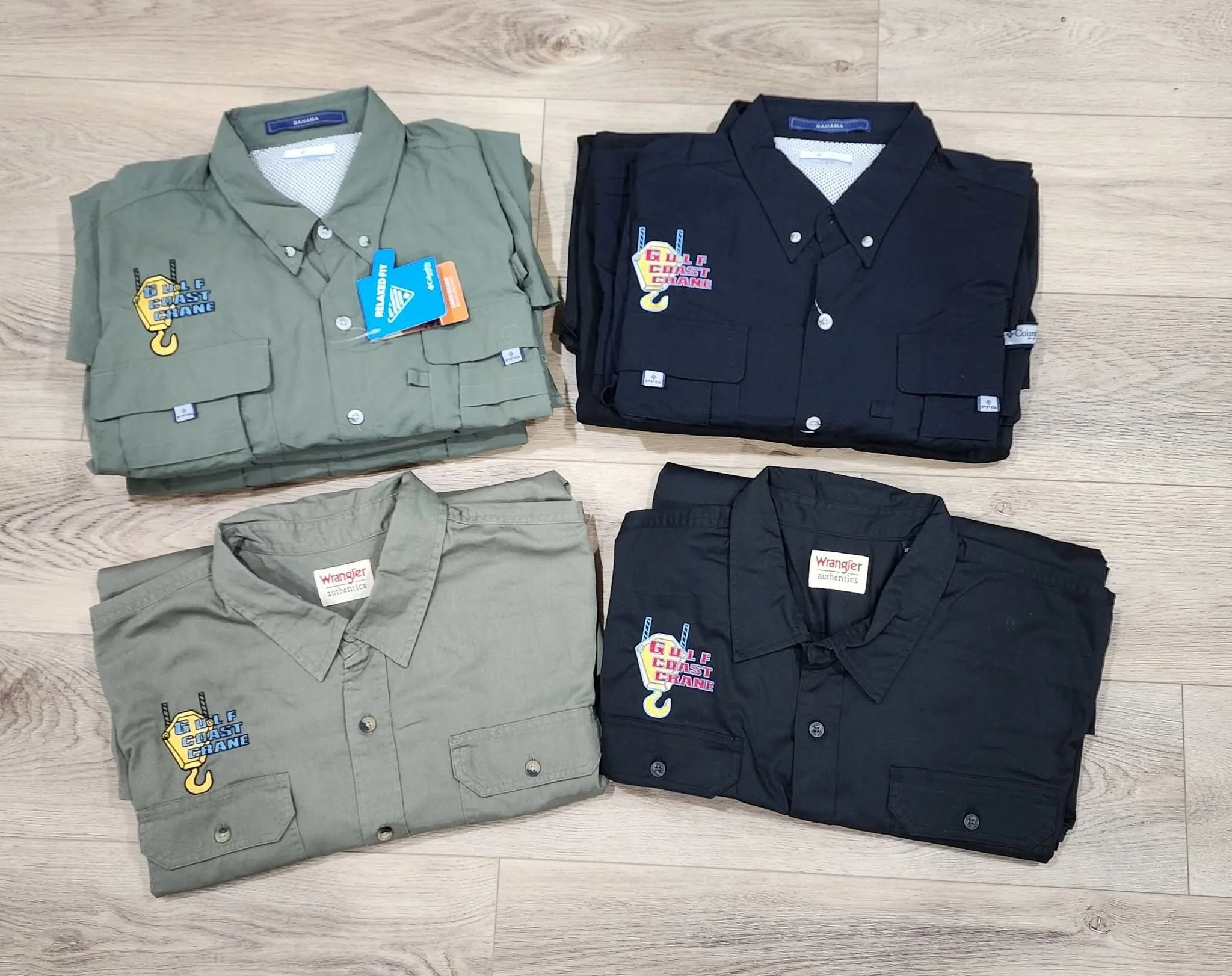 military green and black work shirt with embroidered logo above right pocket displayed on a wooden background