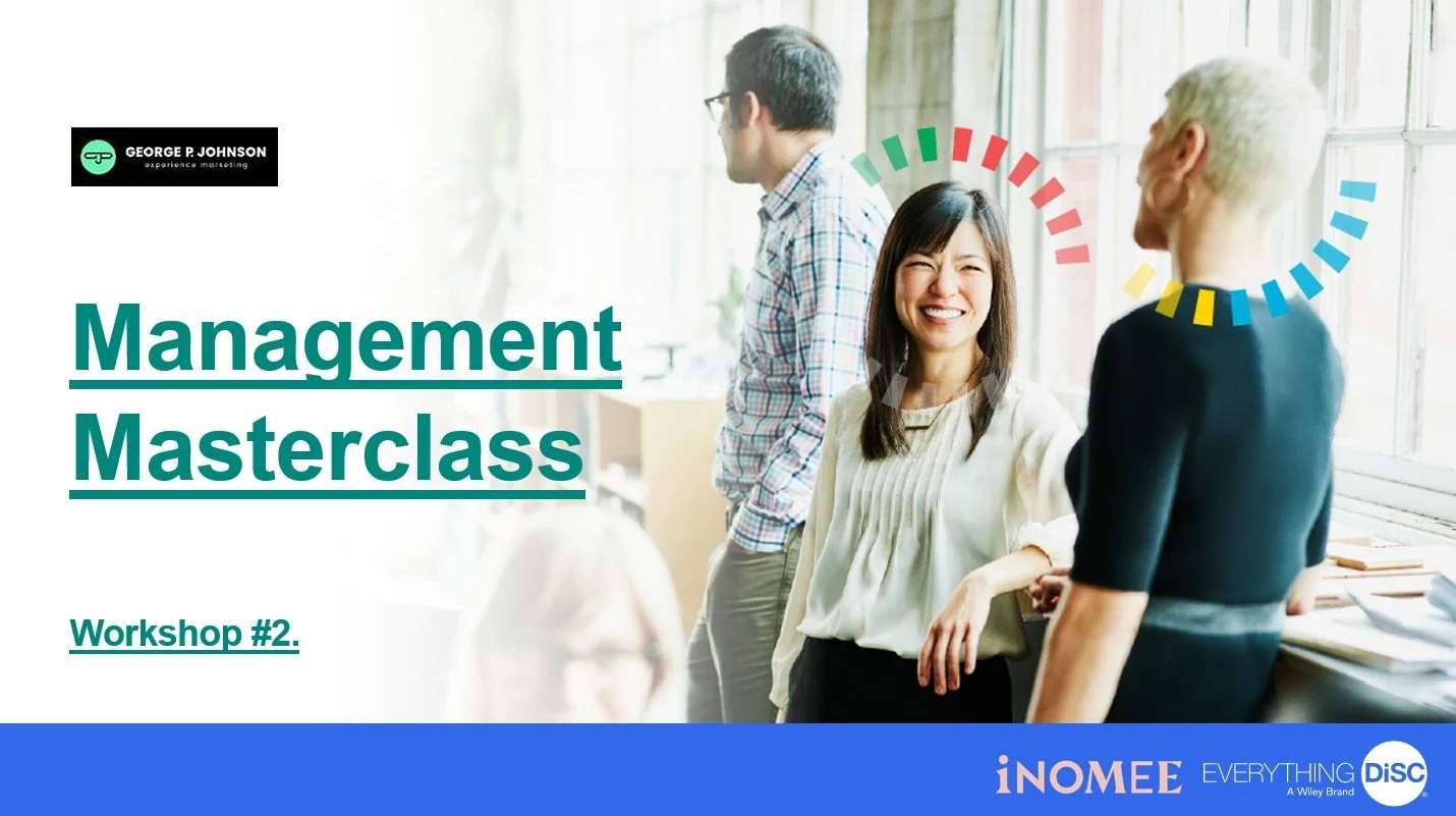 A diverse group of coworkers engaged in a management workshop, smiling and talking by a window in a bright office space.