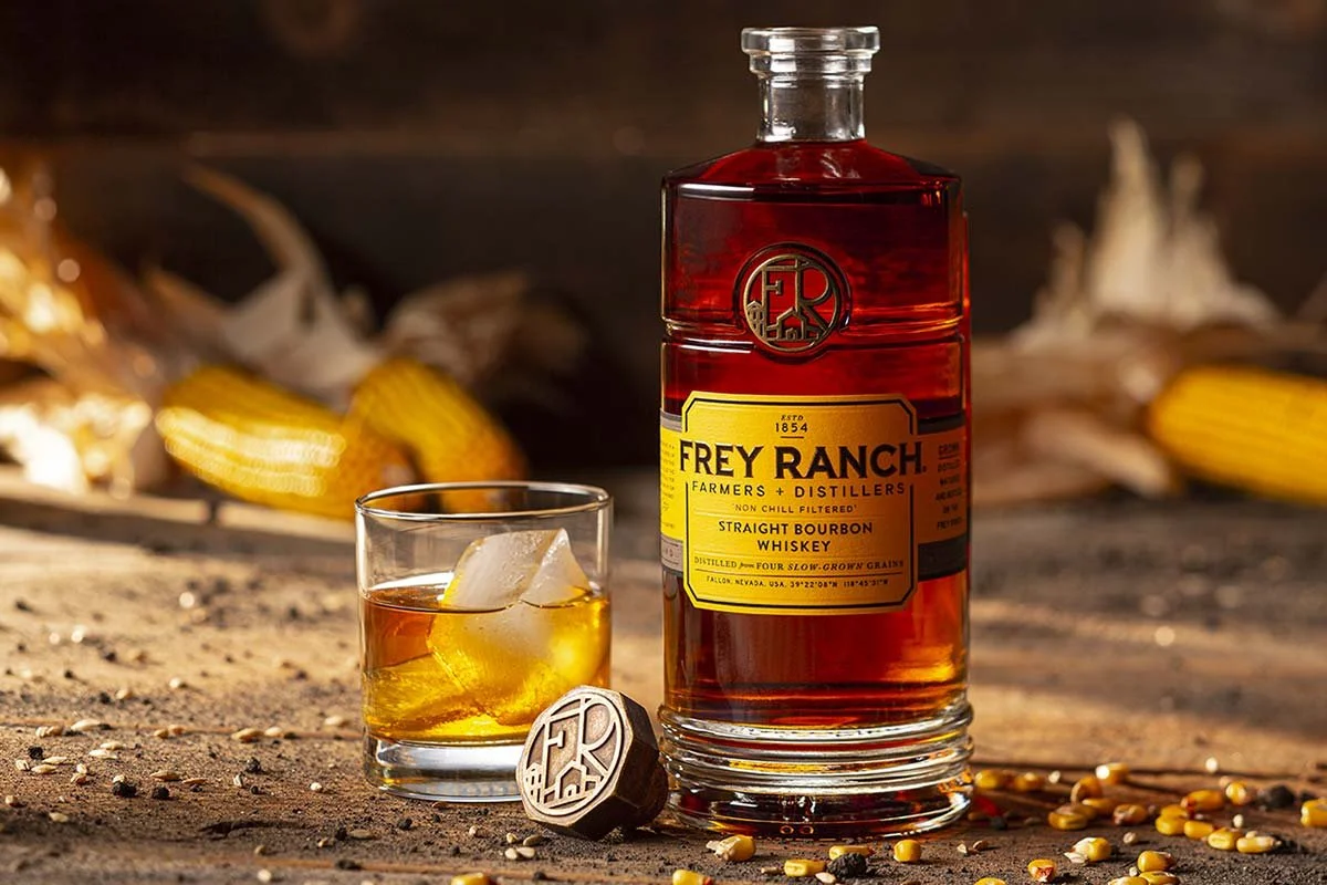 Glass of Bourbon with Ice next to a Bottle of Frey Ranch Straight Bourbon