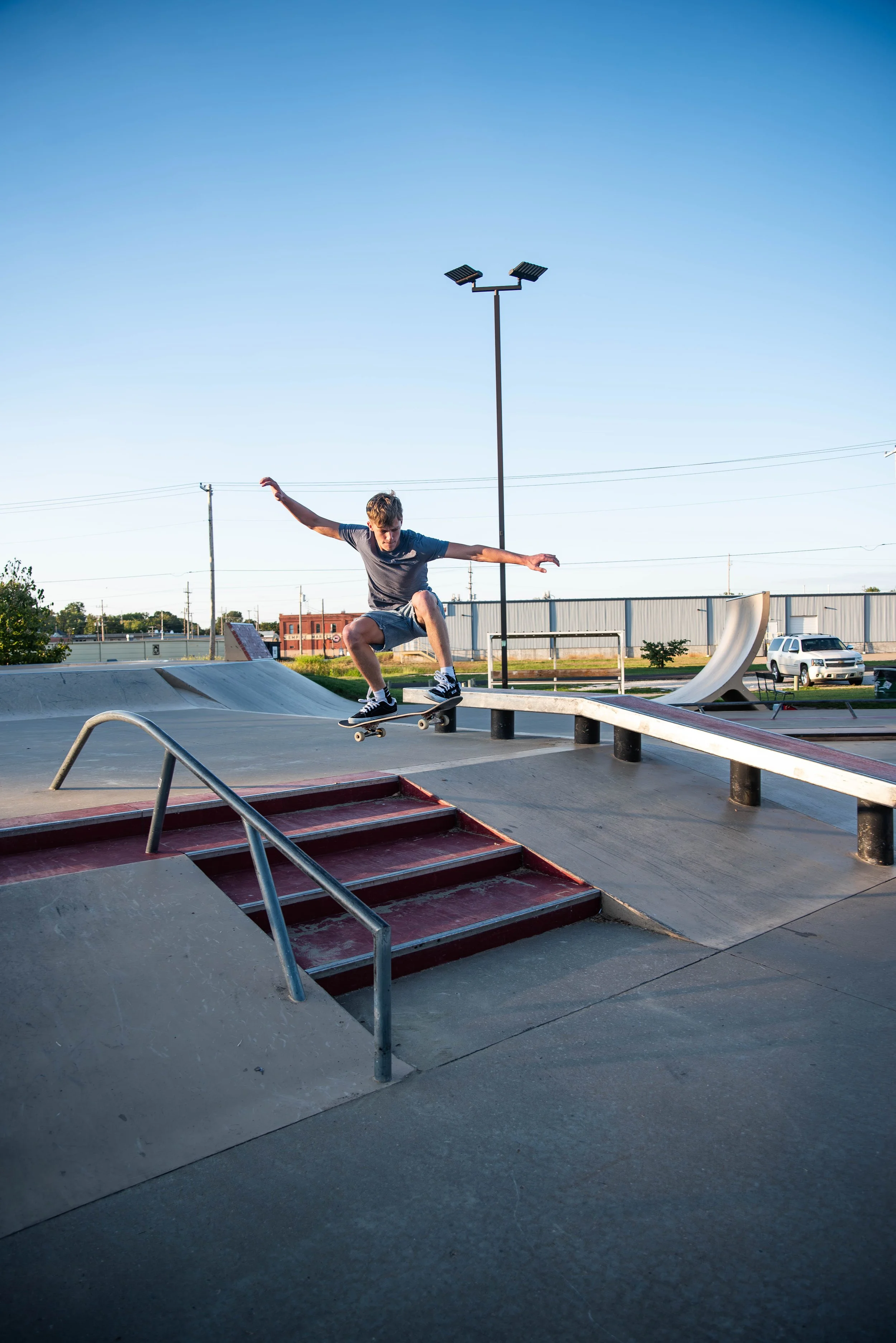 A young boy skateboarding off a ledge at a skatepark during daytime.