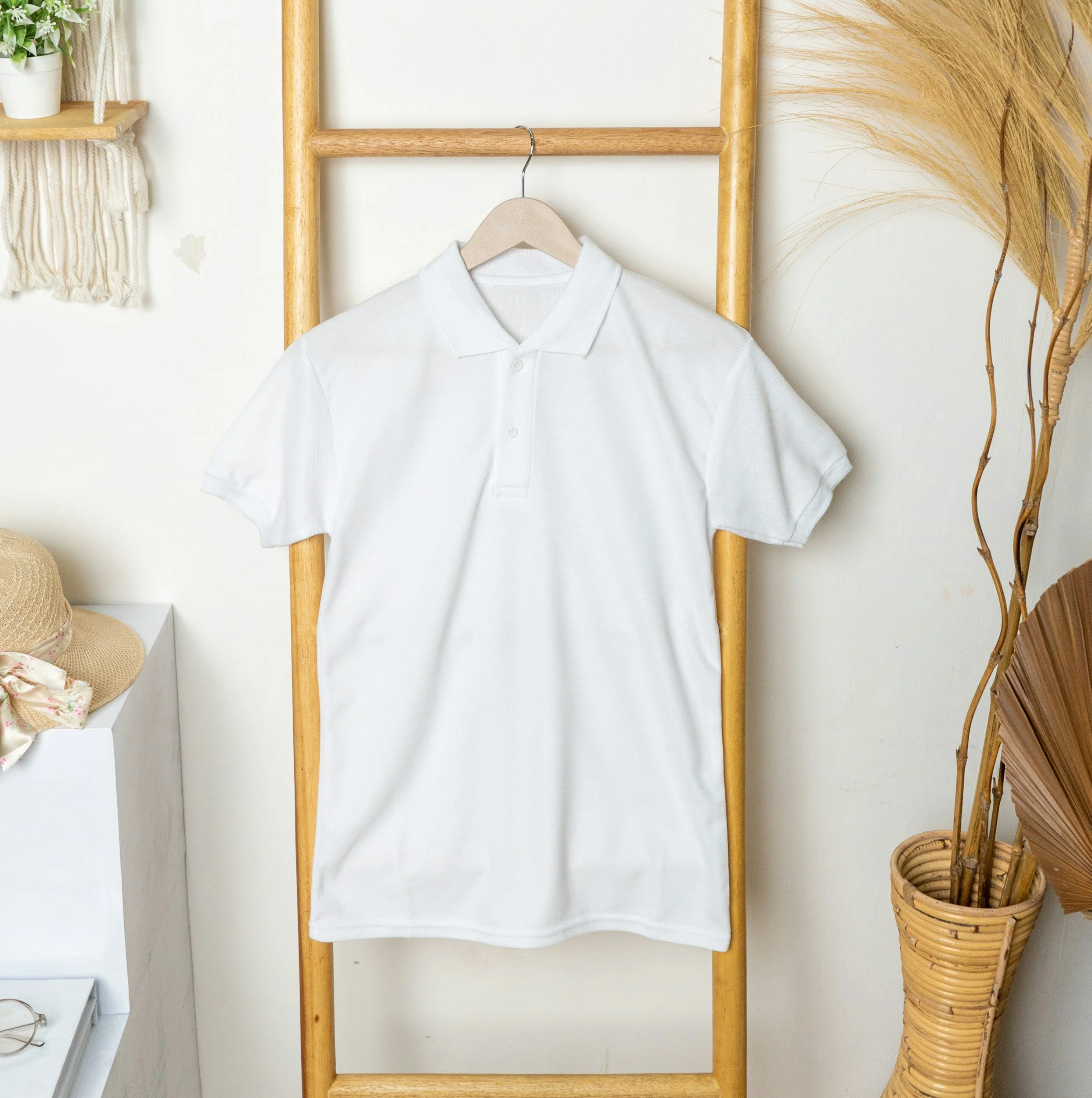 White polo shirt hanging on a wooden ladder in a room with beige and natural decor.