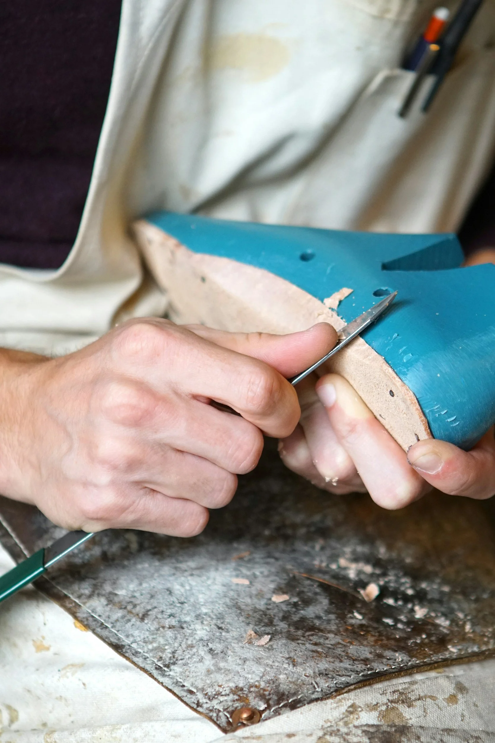 Person carving or detailing a blue surfboard with a metal tool.