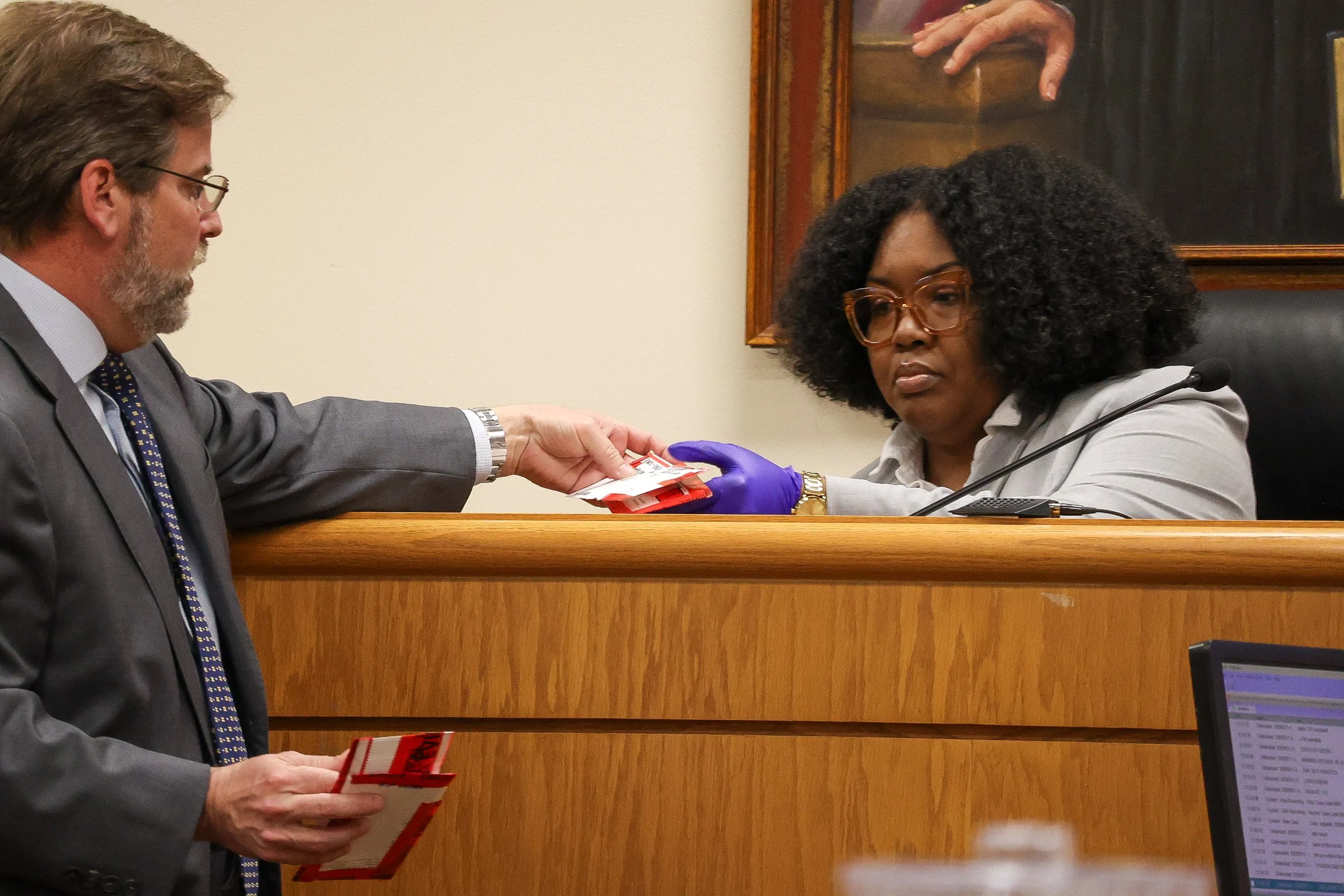 State Attorney Kristopher Bolden hands an envelope to Xykiera Sims on the witness stand during the Tara Baker murder trial at the Athens-Clarke County Courthouse in Athens, Georgia, on Wednesday, Feb. 11, 2026. Sims tested three DNA swabs associated 