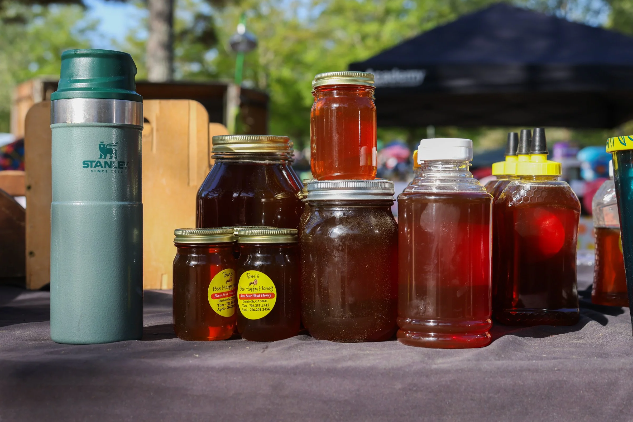 Jars of honey sit on top of Tom Hankins's honey stand at the J&J Flea Market in Athens, Georgia, on April 5, 2025. Tom Hankins offers raw honey and beeswax, products he has sold at the market for over seven years, highlighting its health benefits.