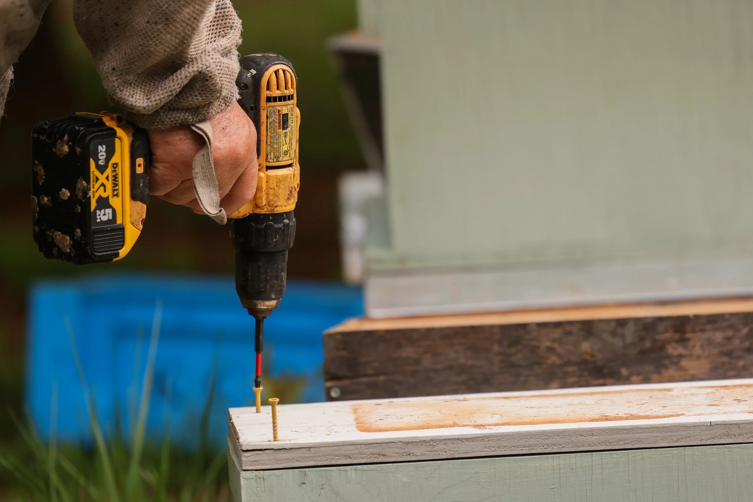 Tom Hankins drills the lid to a beehive shut in Danielsville, Georgia, on April 14, 2025. The bees enter and exit through a hole on the exterior of the hive.
