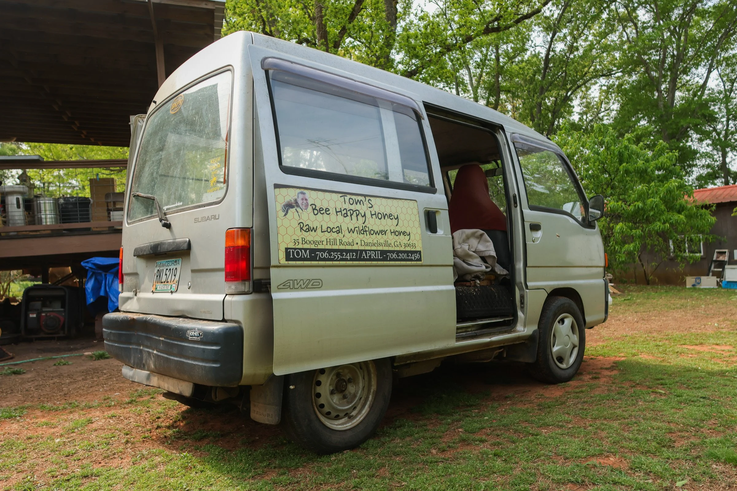 Tom Hankins's bee van parked in his backyard in Danielsville, Georgia, on April 14, 2025. Tom Hankins uses the old Subaru van to haul his honey and bee-keeping equipment. Haskins also uses the van for advertisement, with a picture of his head attache