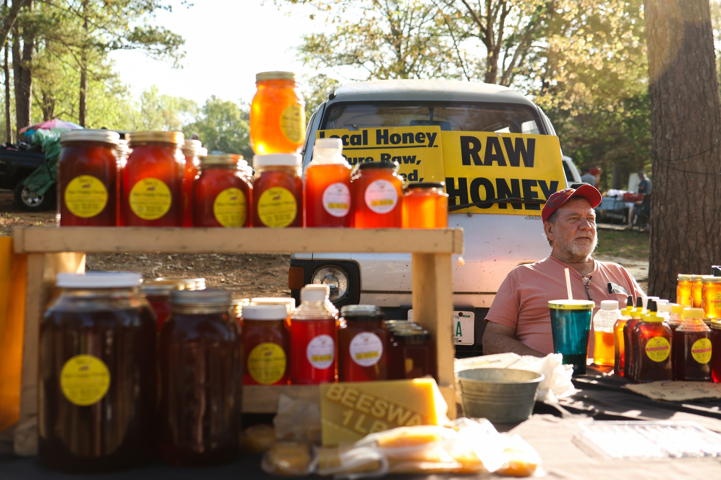 Beekeeper Tom Hankins displays jars of raw honey at his stand at the J&J Flea Market in Athens, Georgia, on April 5, 2025. He has been selling his unpasteurized local honey at the market for over seven years, offering customers a taste of its health 