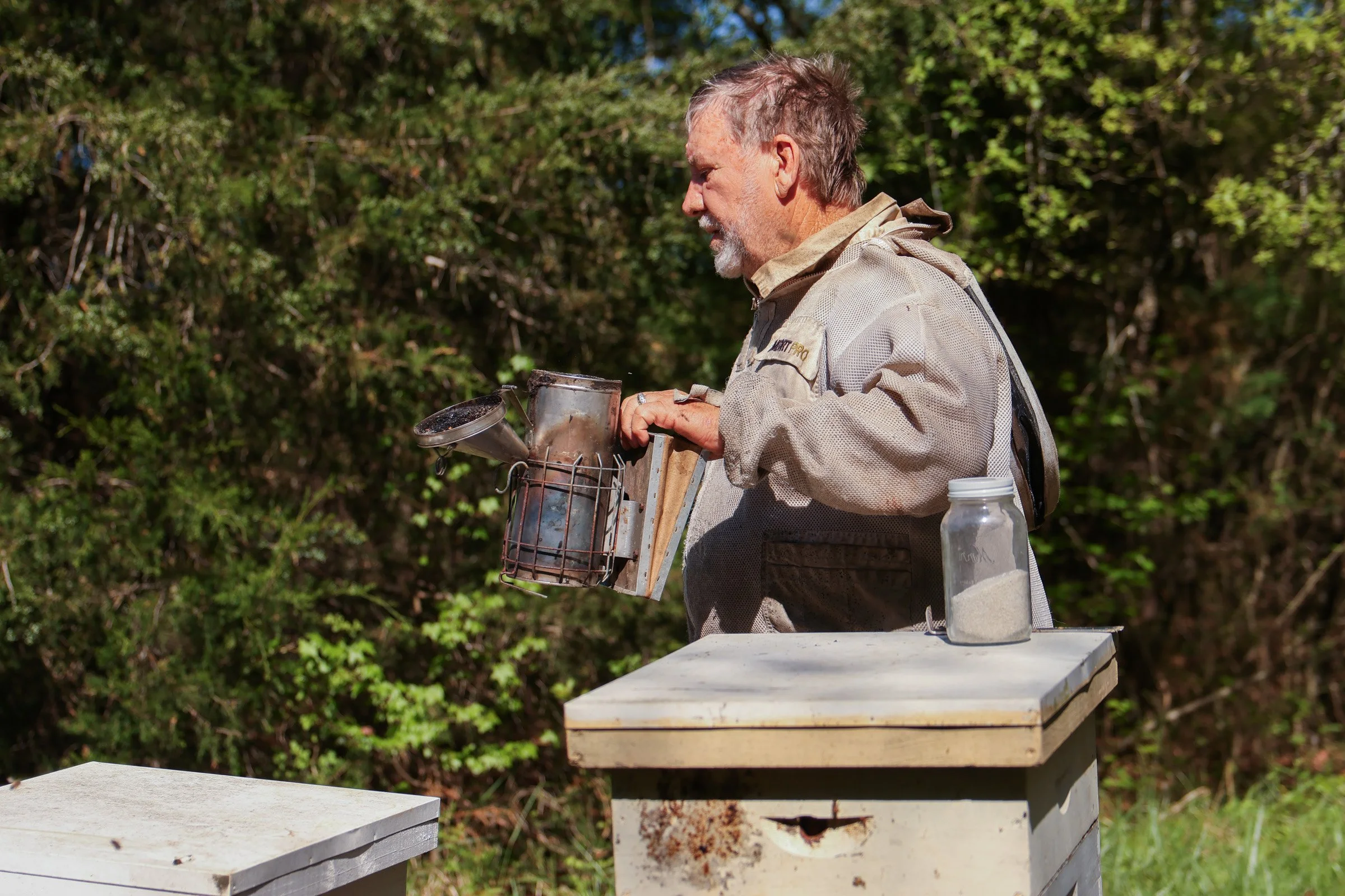 Tom Hankins tends to his beehives while holding a smoker in Danielsville, Georgia, on April 14, 2025. Hankins uses the smoke before opening the bee hives to prevent himself from being stung. 