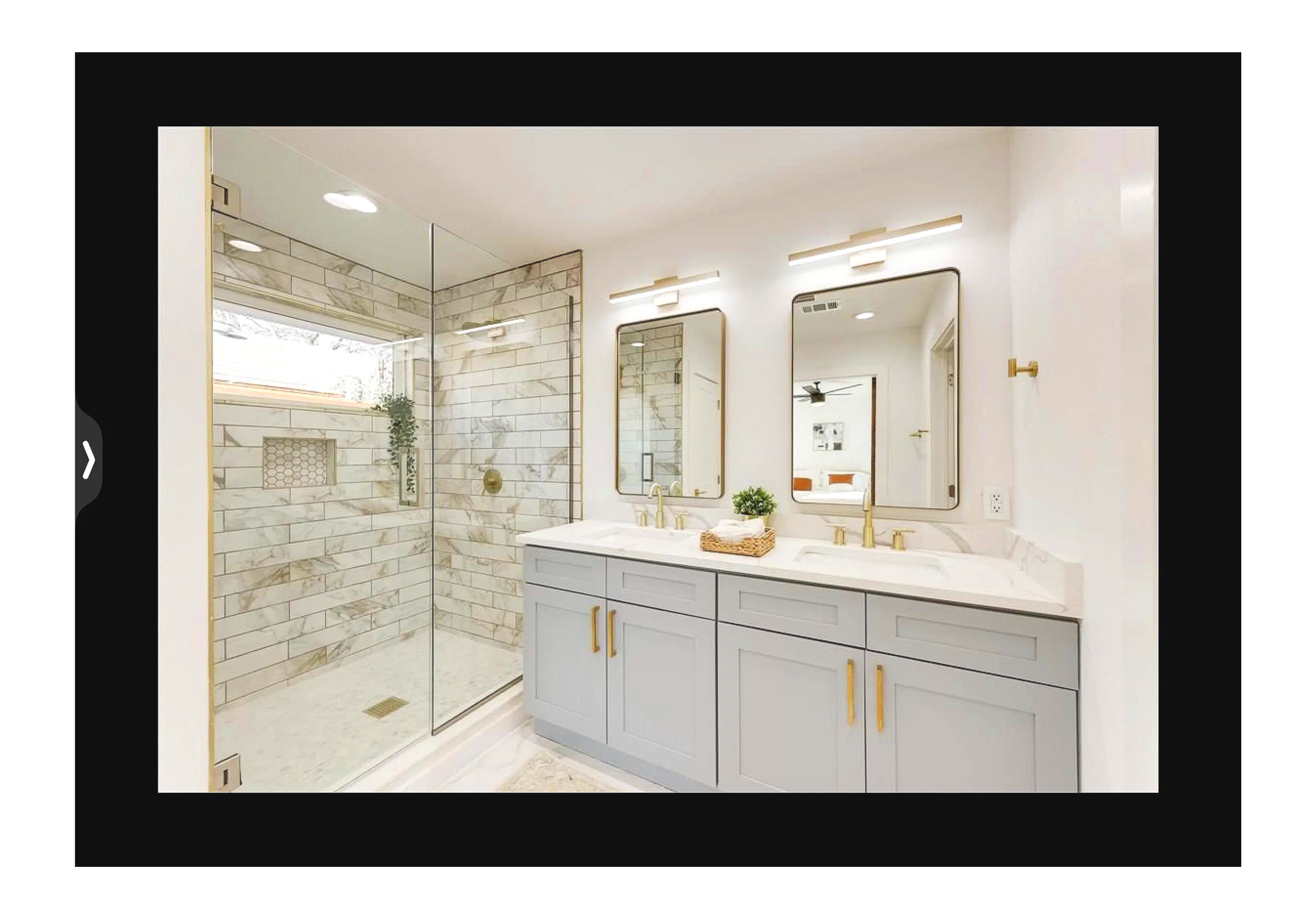 Modern bathroom with double vanity with light blue cabinets, gold hardware, large mirrors, and a walk-in glass shower with marble tiles, a niche, and a window.