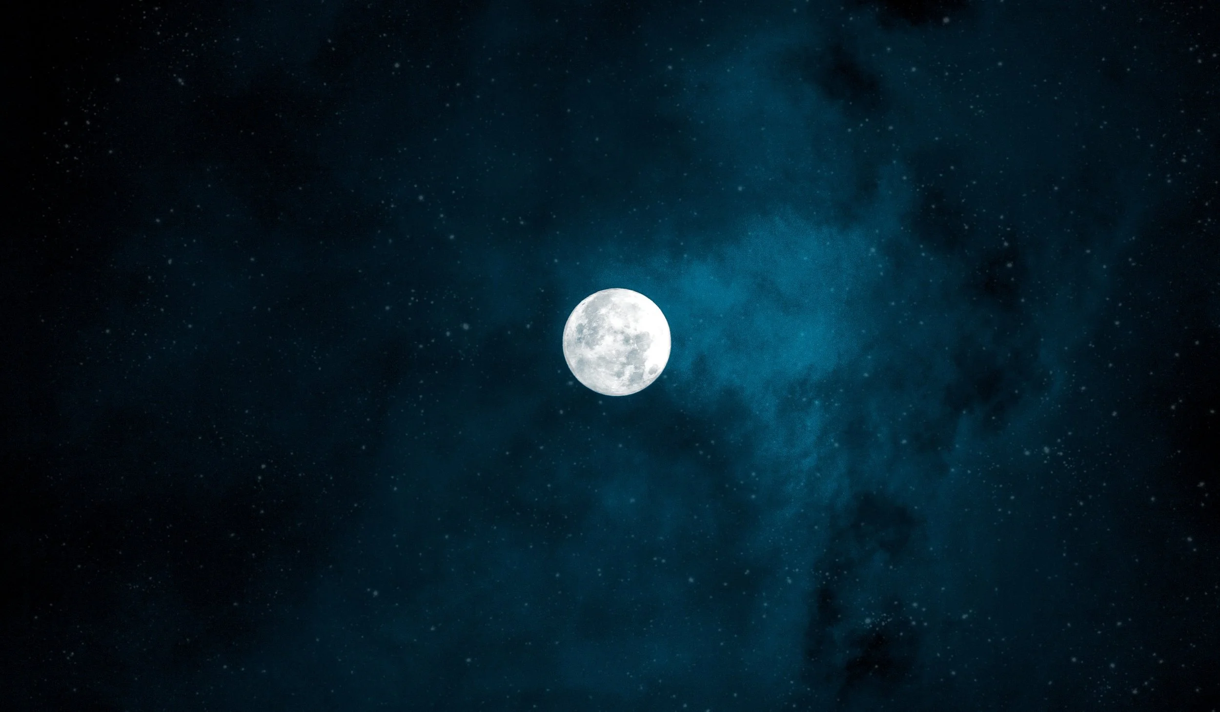 A full moon in a starry night sky with some wispy clouds.