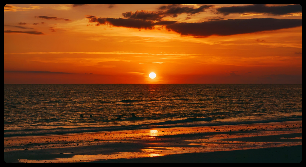Orange sunset over the ocean, the sun low on the horizon.