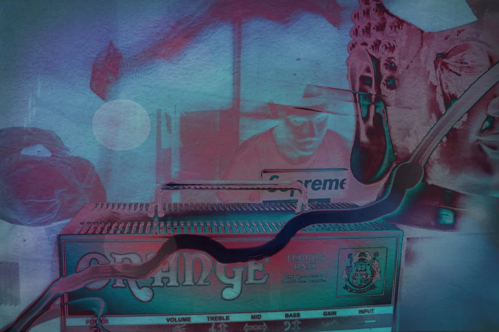 Color-inverted image of a guitarist playing over an Orange amplifier.