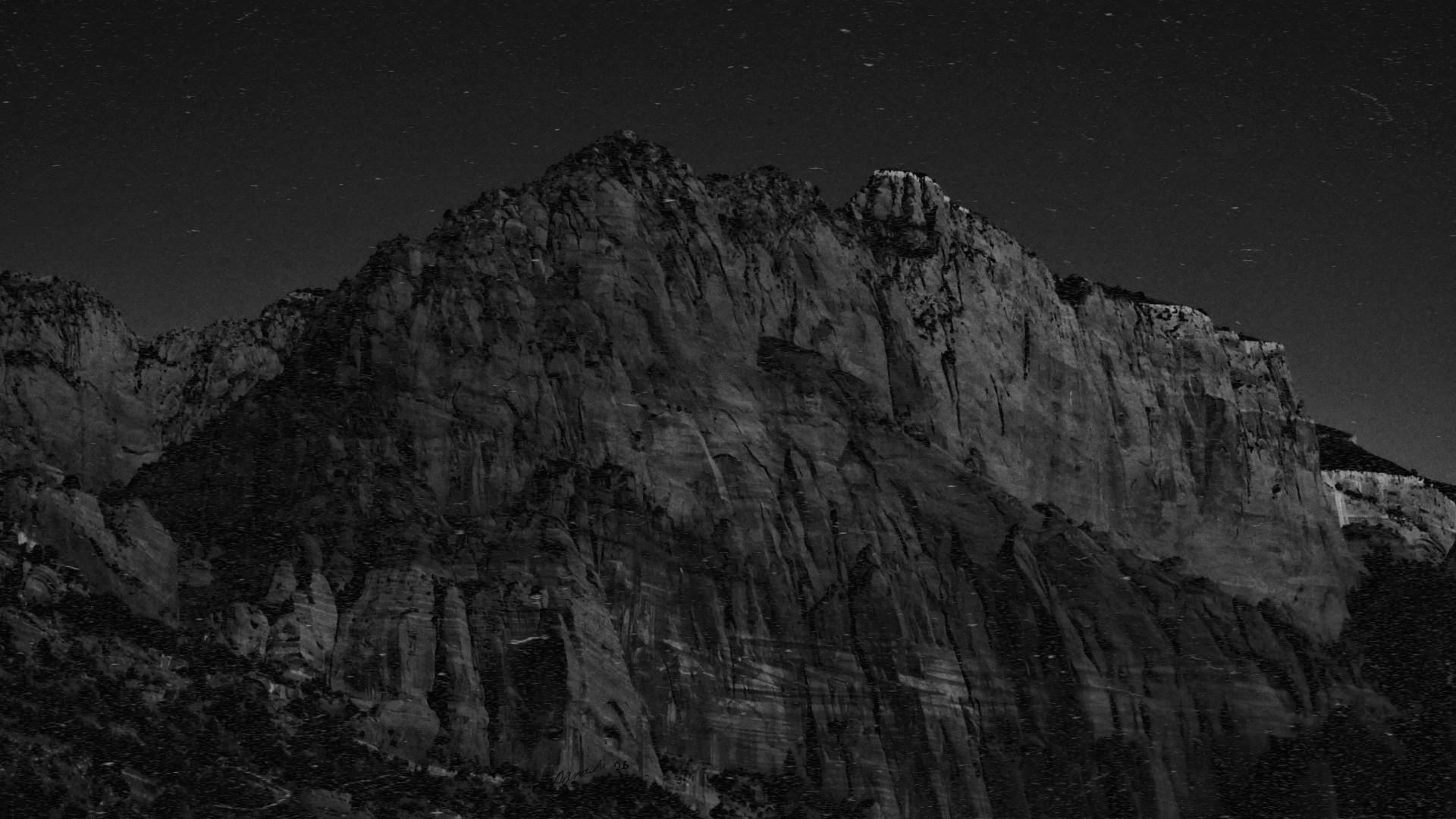 A towering, textured mountain cliff illuminated against a dark sky filled with stars, depicted in grayscale.
