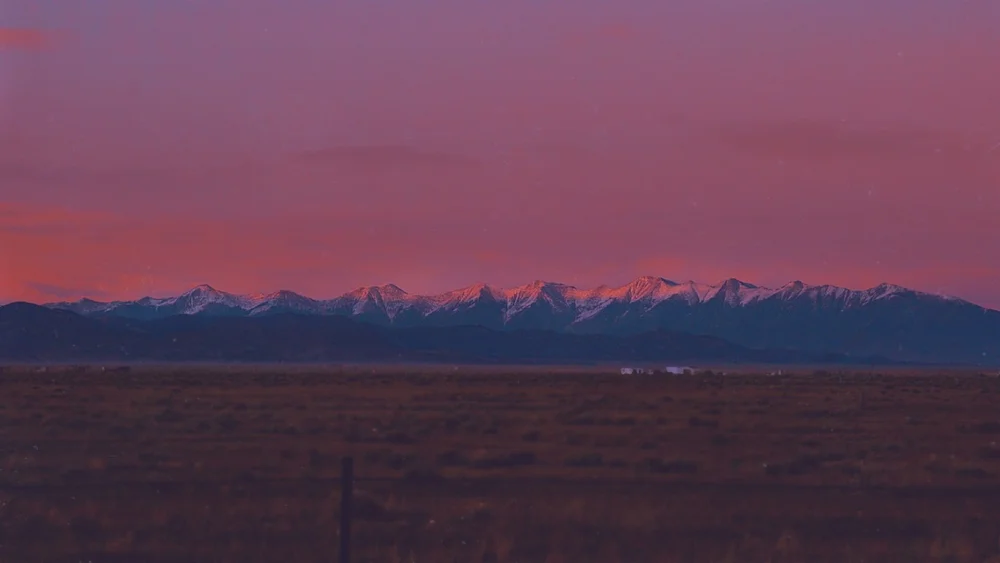 Pink sky over a distant snow-capped mountain range.