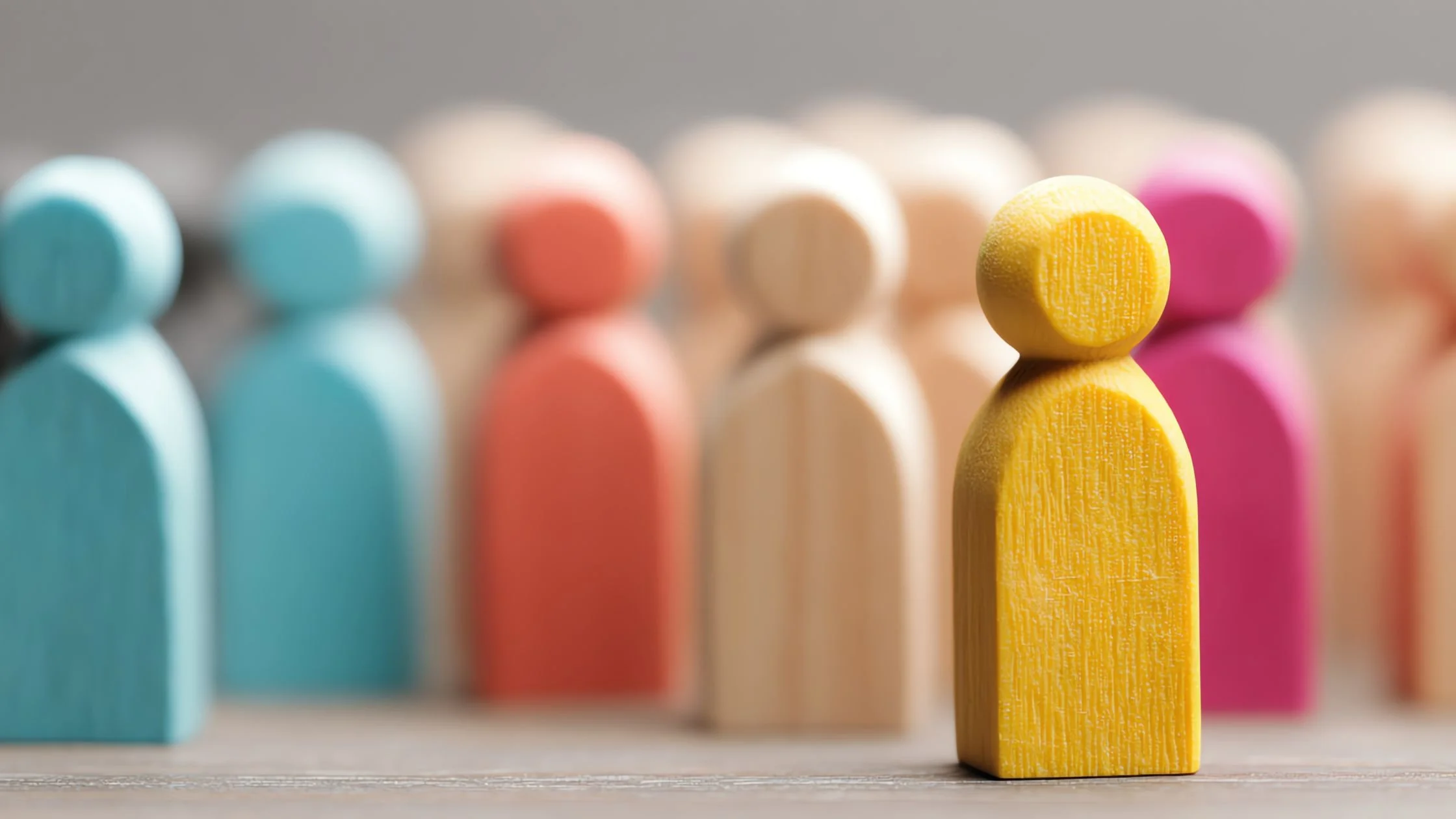 Colorful wooden figurines arranged in a row with a yellow one in the foreground.