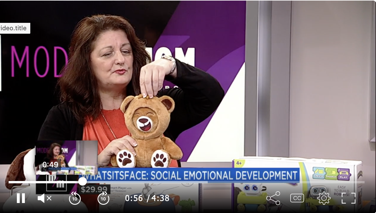 A woman holding a plush teddy bear, performing a demonstration during a television segment about social emotional development.