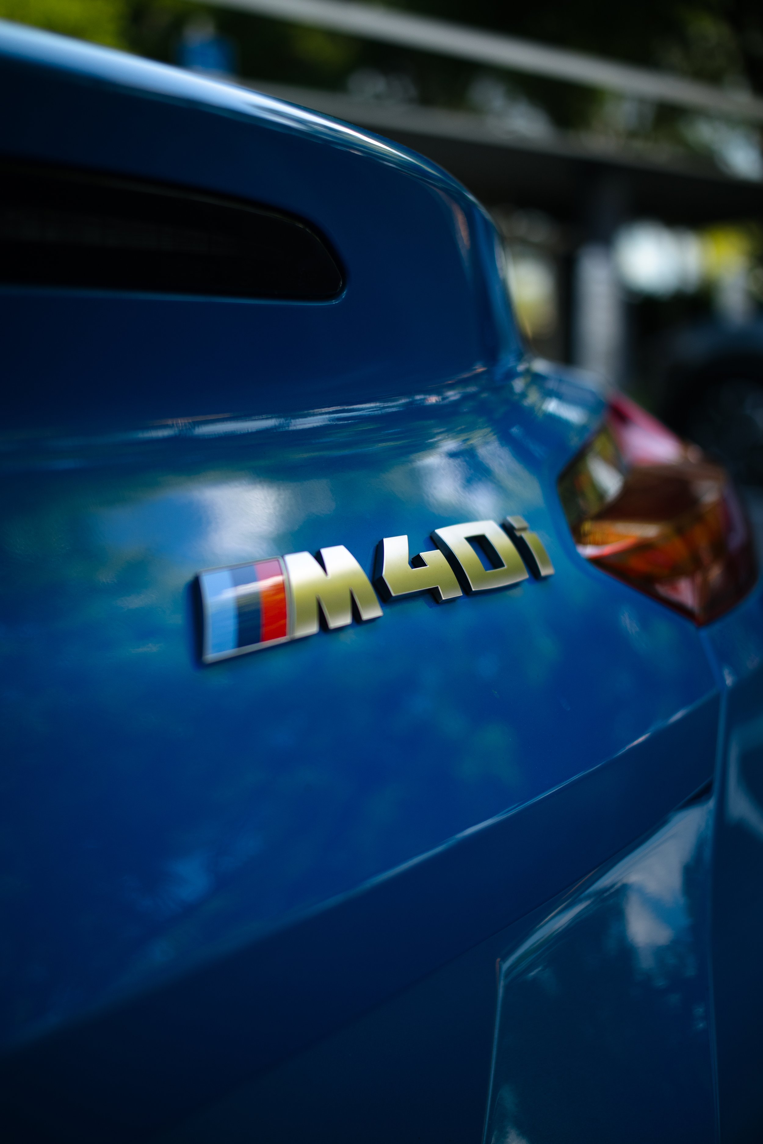 Close-up of the rear of a blue vehicle with an M40i badge.