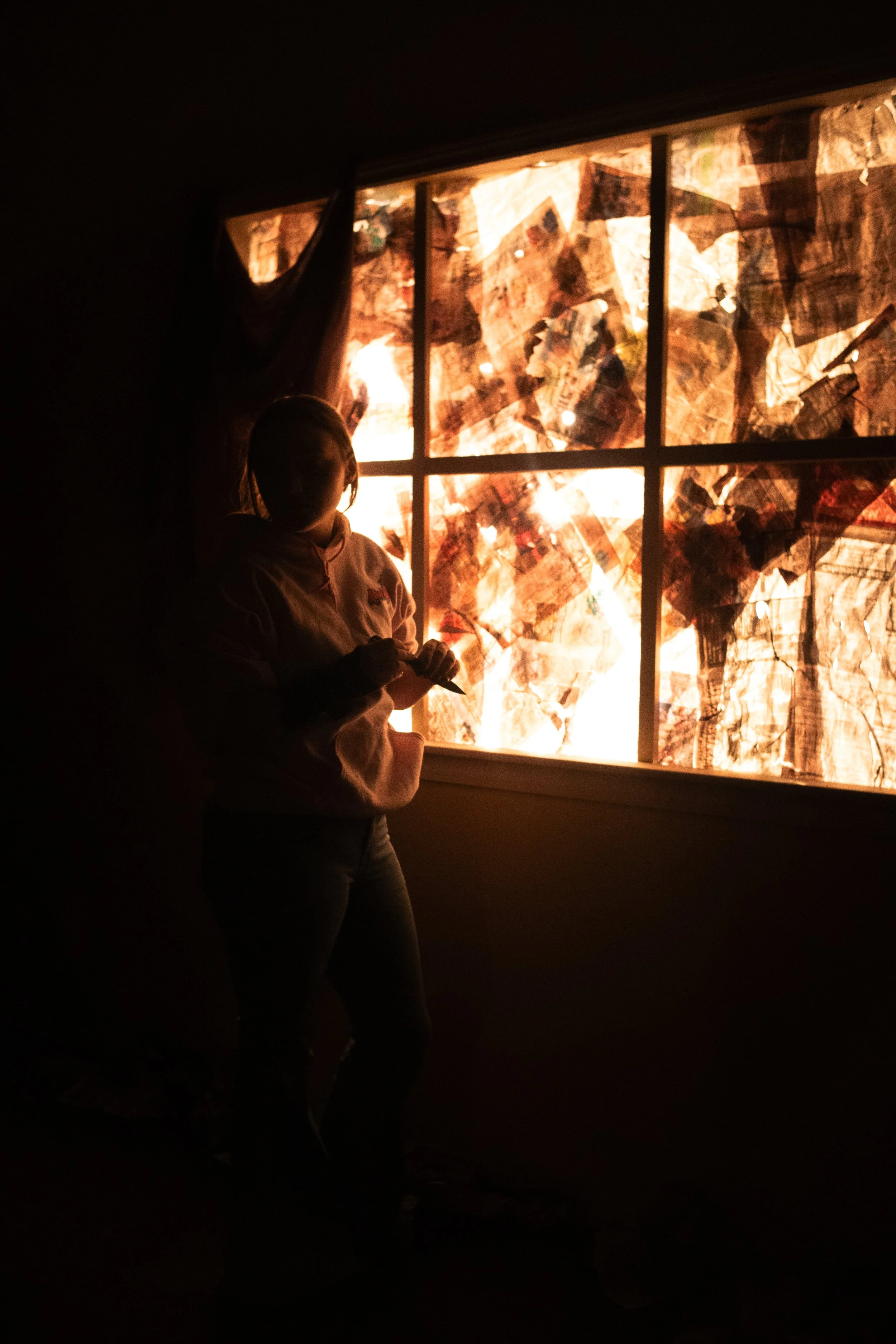 Silhouettes of two children in front of a brightly lit, colorful stained glass window.