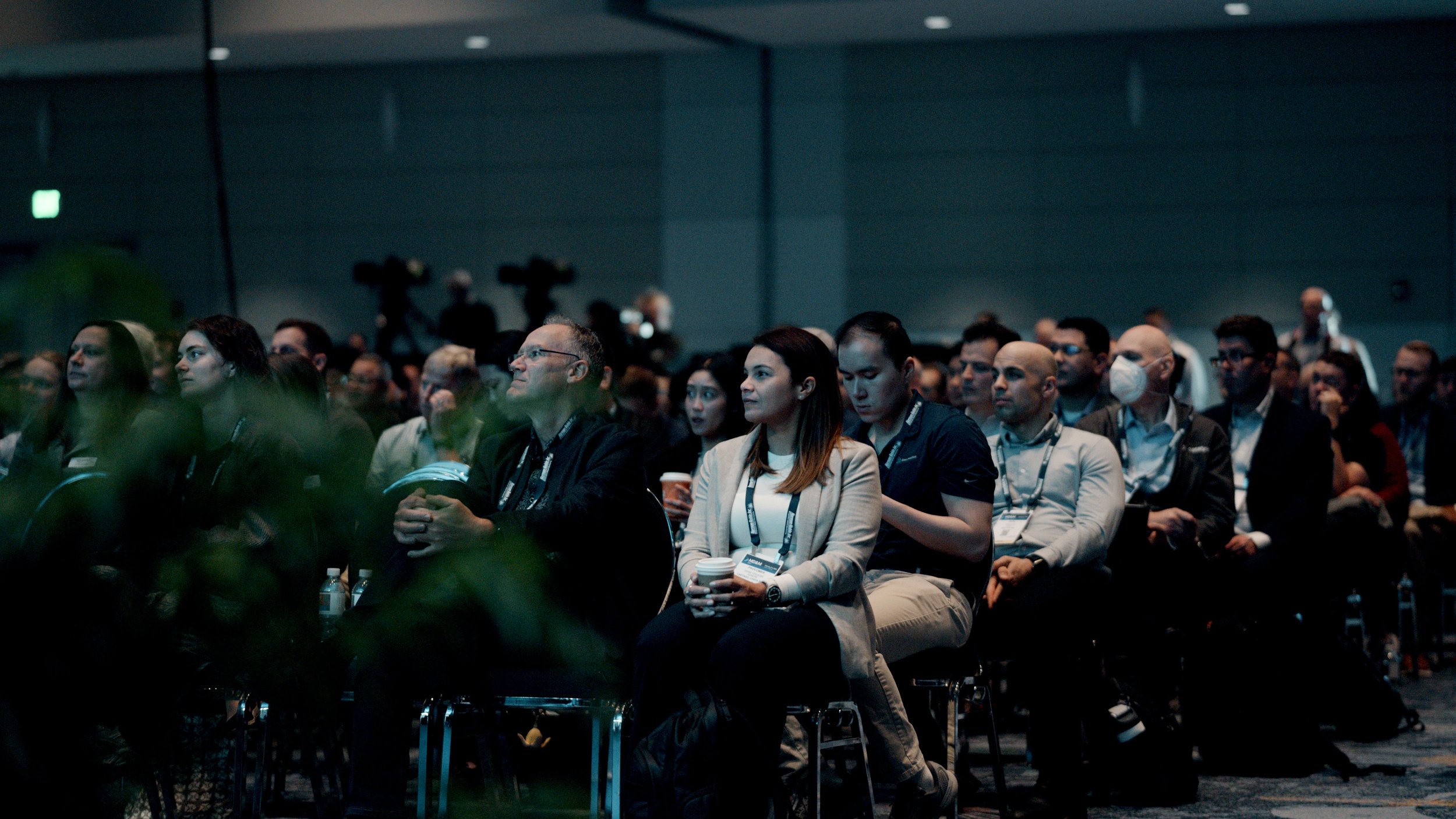 Audience seated in a conference room listening attentively during a presentation.