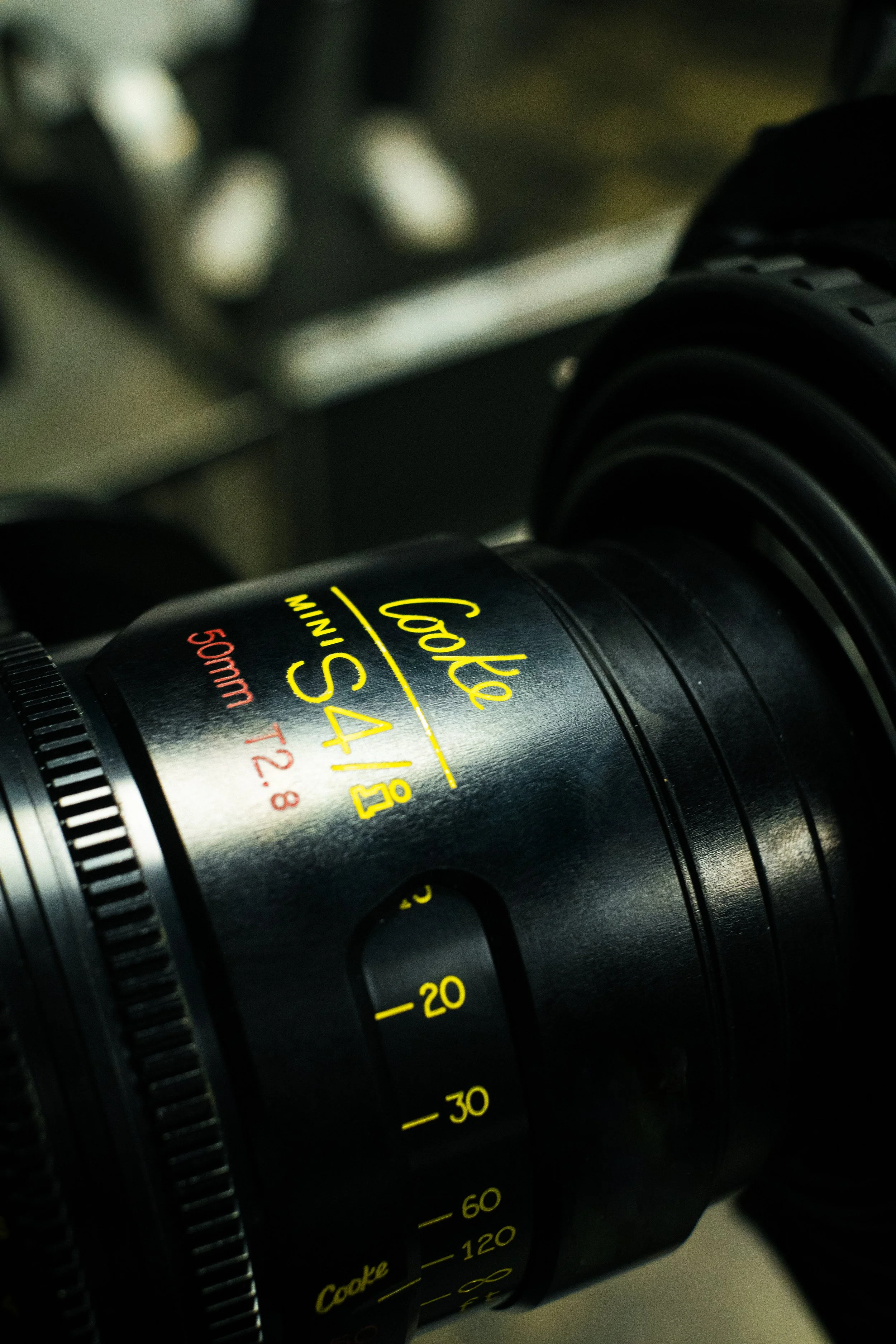 Close-up of a camera lens with yellow and red markings, including the words 'Cooke' and 'MiniS4'.