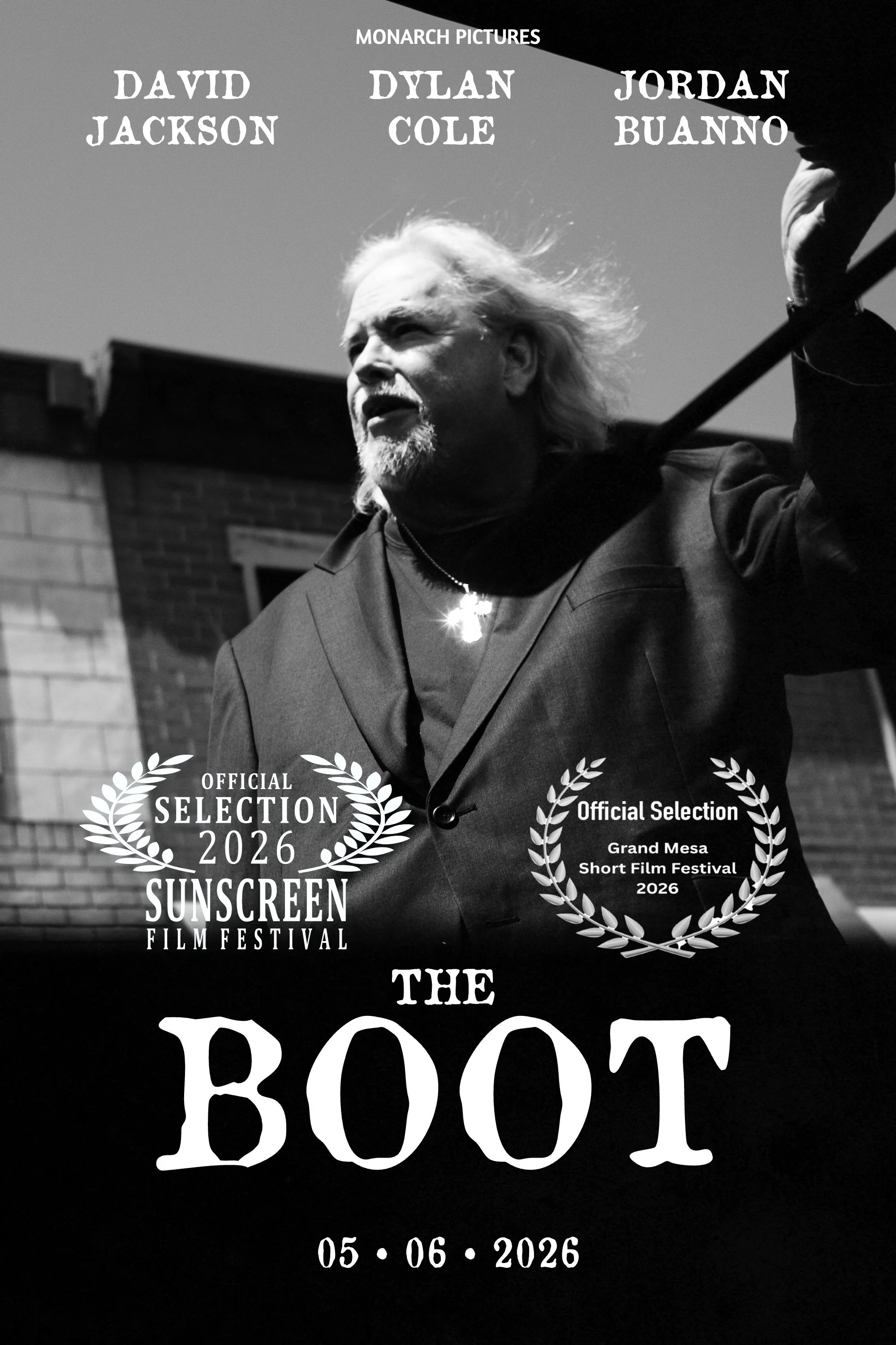 Black and white photograph of an older man with long hair and a beard, holding a tree branch over his shoulder, standing outdoors with a brick building and window in the background. The image is overlaid with text and laurels, indicating it is from t