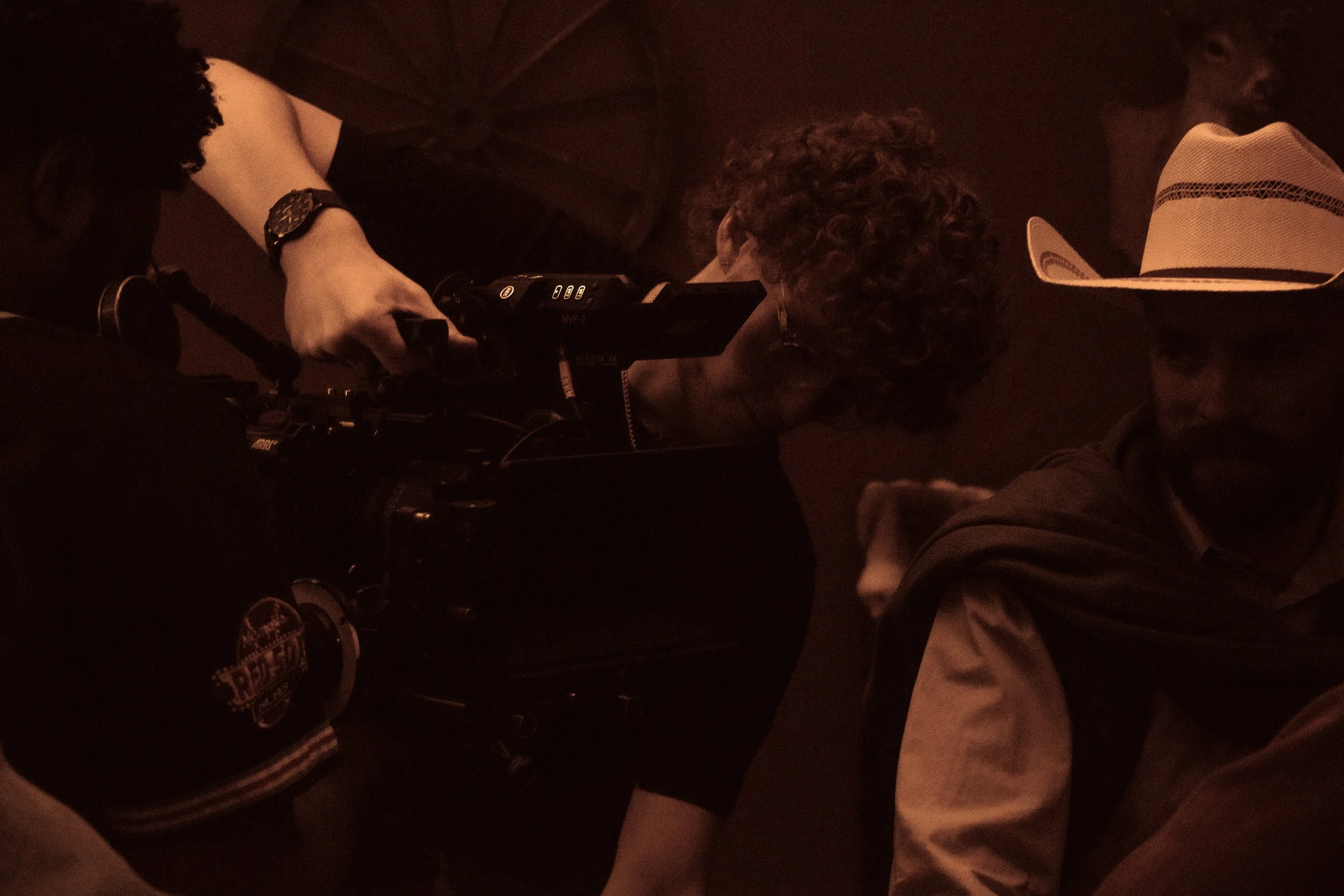 People under a dark umbrella in a dimly lit setting.