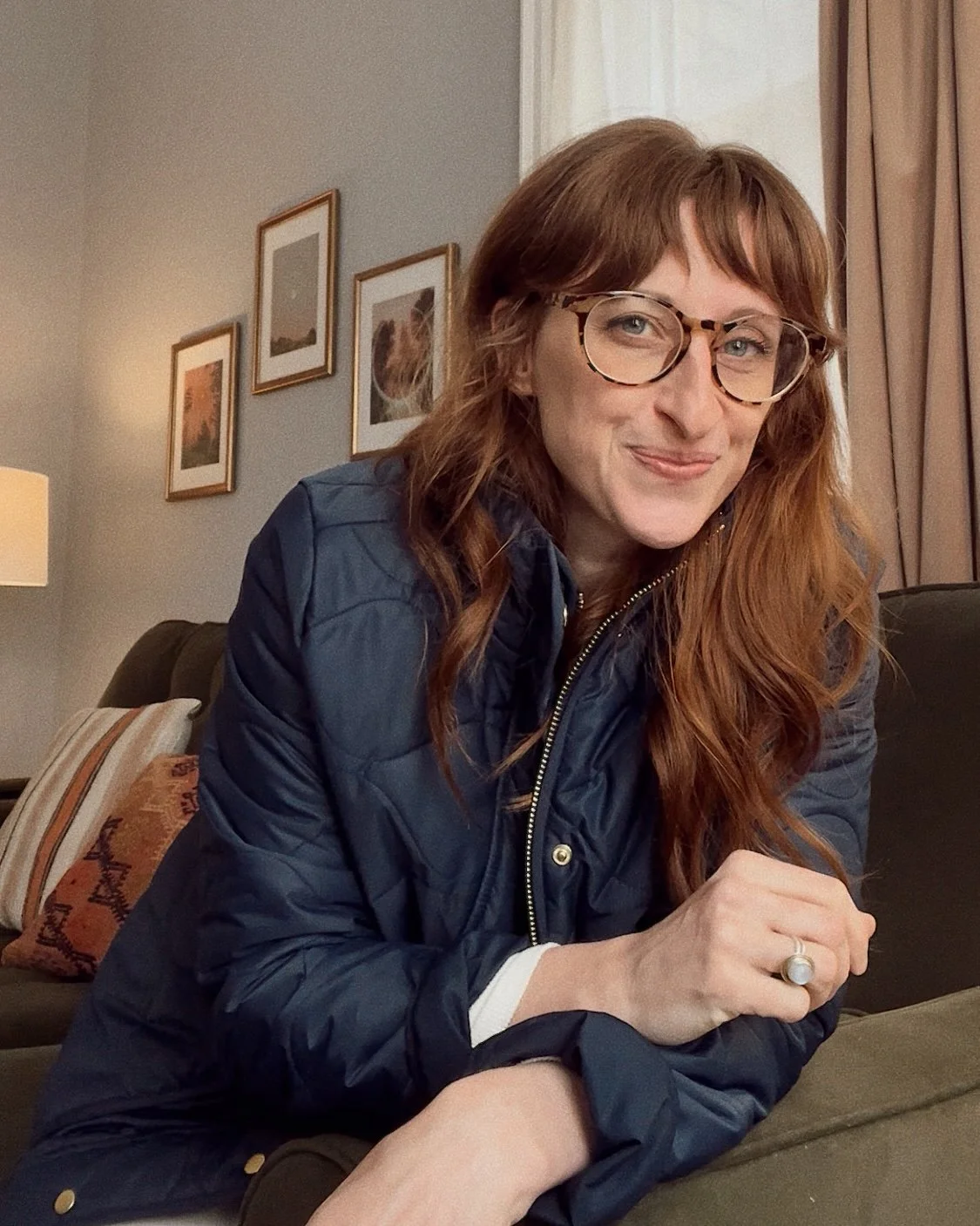 Carley Irwin, LPC, therapist in Akron, Ohio, sitting on a couch in her psychotherapy office