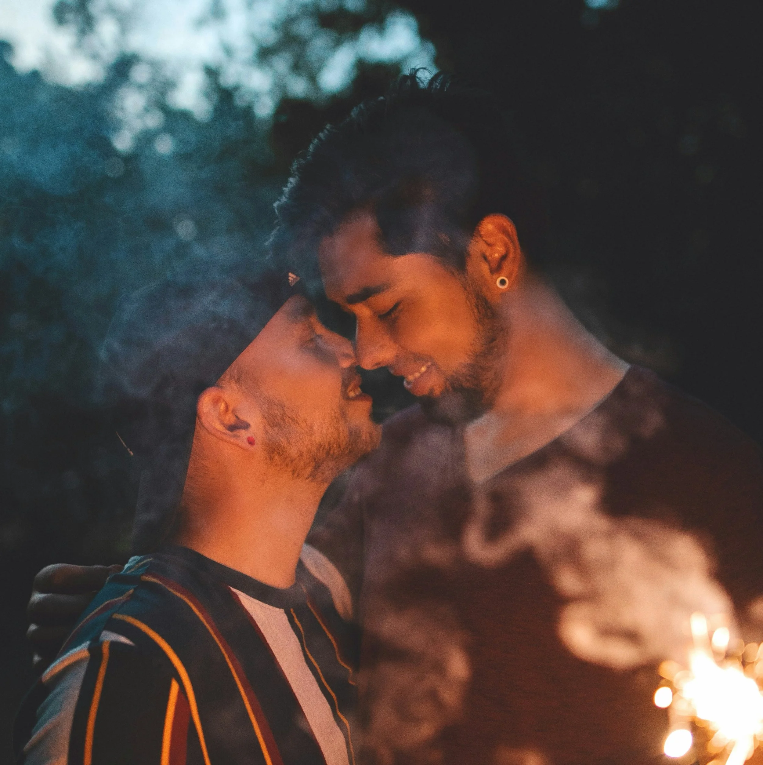Two men in a relationship standing close leaning in to kiss