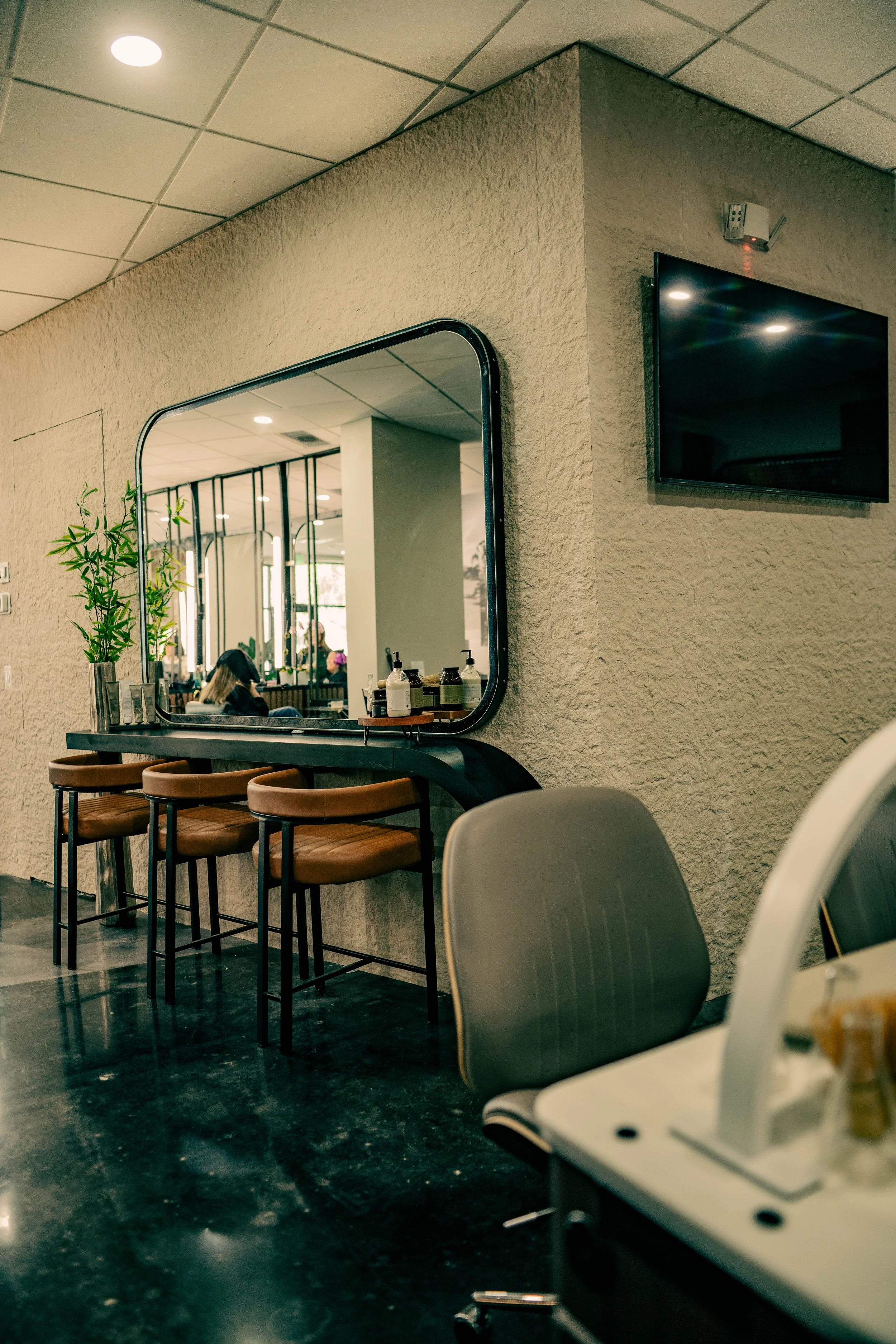 The services header for Très Ivanhoe Salon, featuring a styling station mirror and premium products, inviting clients to explore our Hair, Nails, and Head Spa menu.