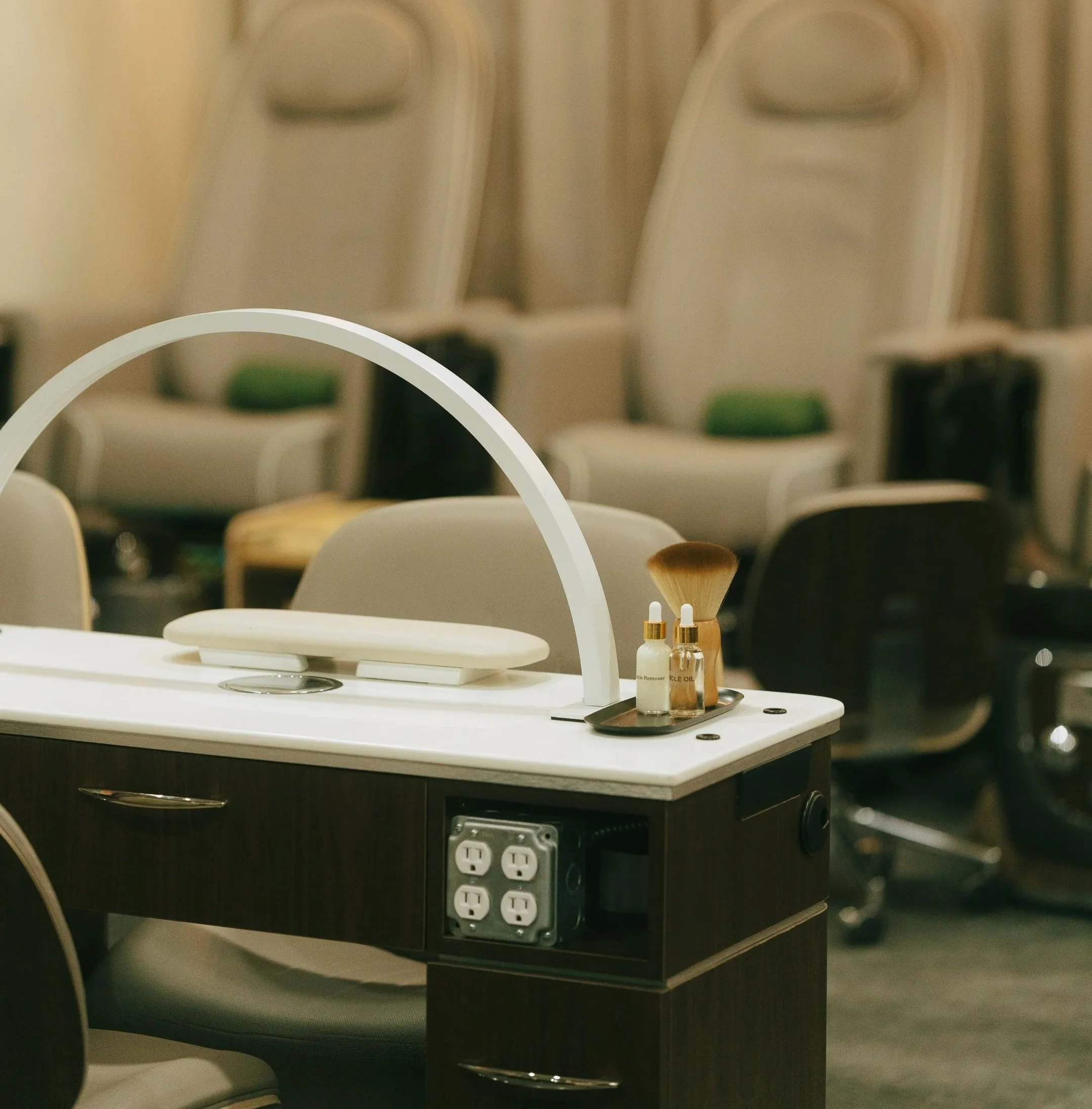 A pristine manicure station with plush pedicure chairs in the background at Très Ivanhoe Salon, dedicated to nail precision and clean formulas.