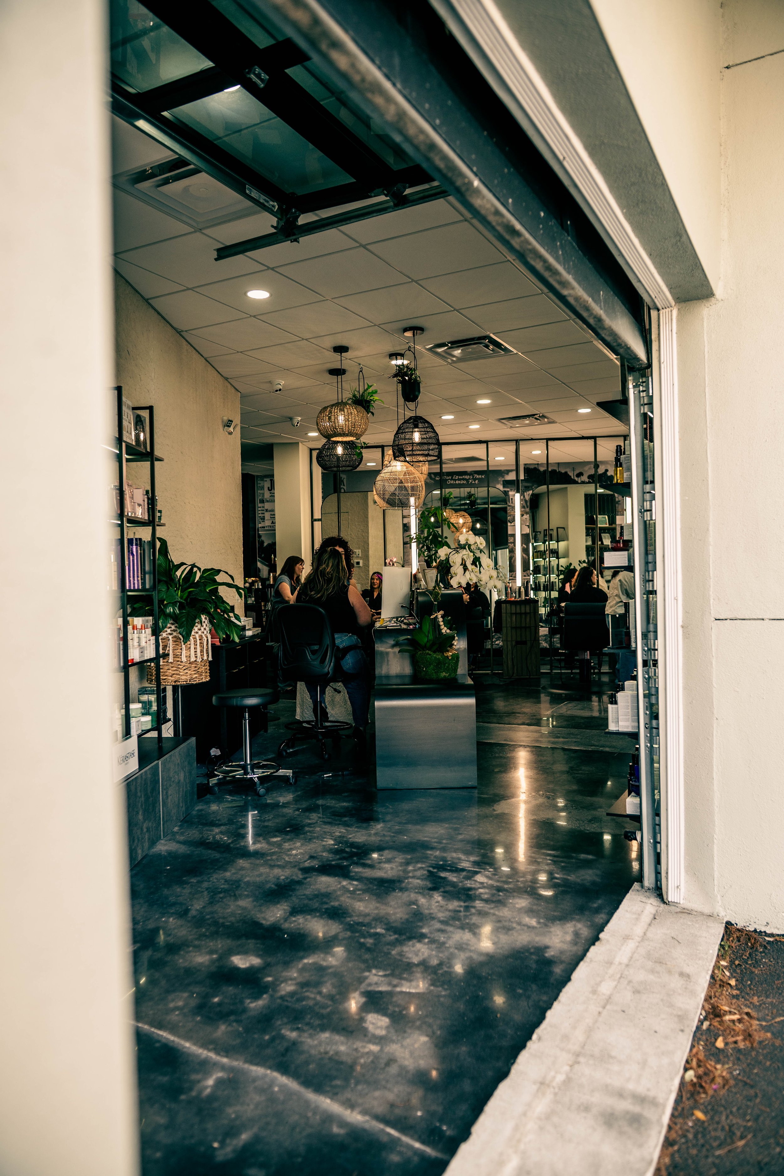The modern, open-concept interior of Très Ivanhoe Salon in Orlando, featuring industrial-chic design, woven pendant lighting, and a relaxing atmosphere.