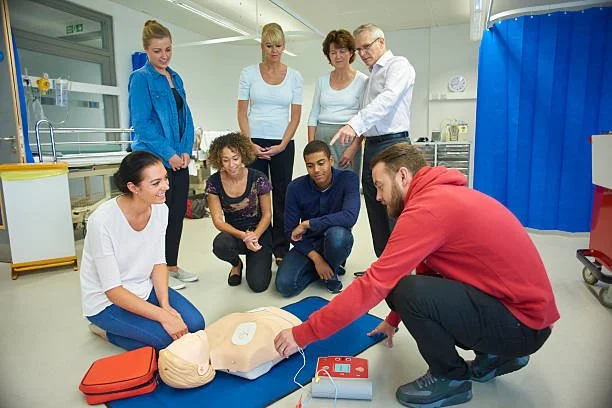 Group of medical students and instructor practicing CPR on a mannequin in a classroom.