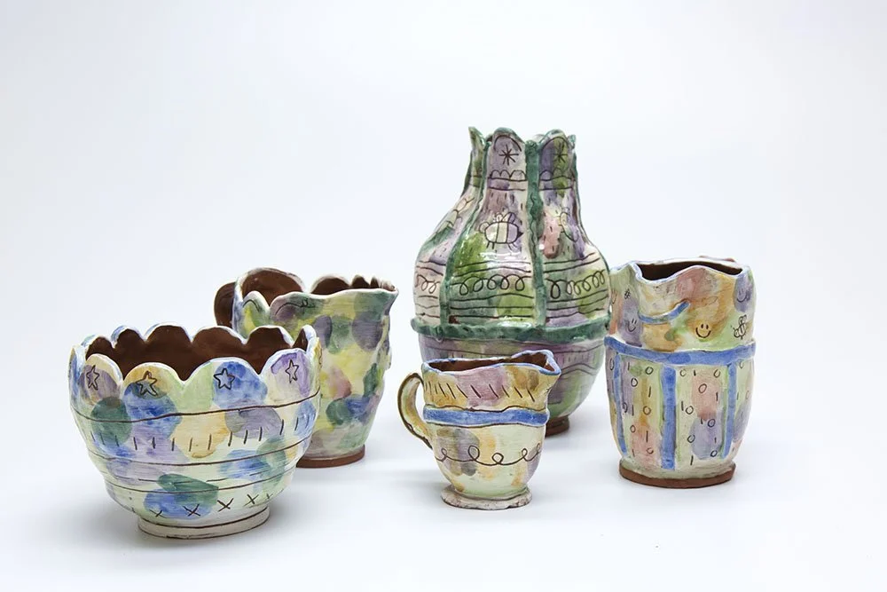 Colorful, hand-painted ceramic vases and bowls with whimsical designs on a white background.