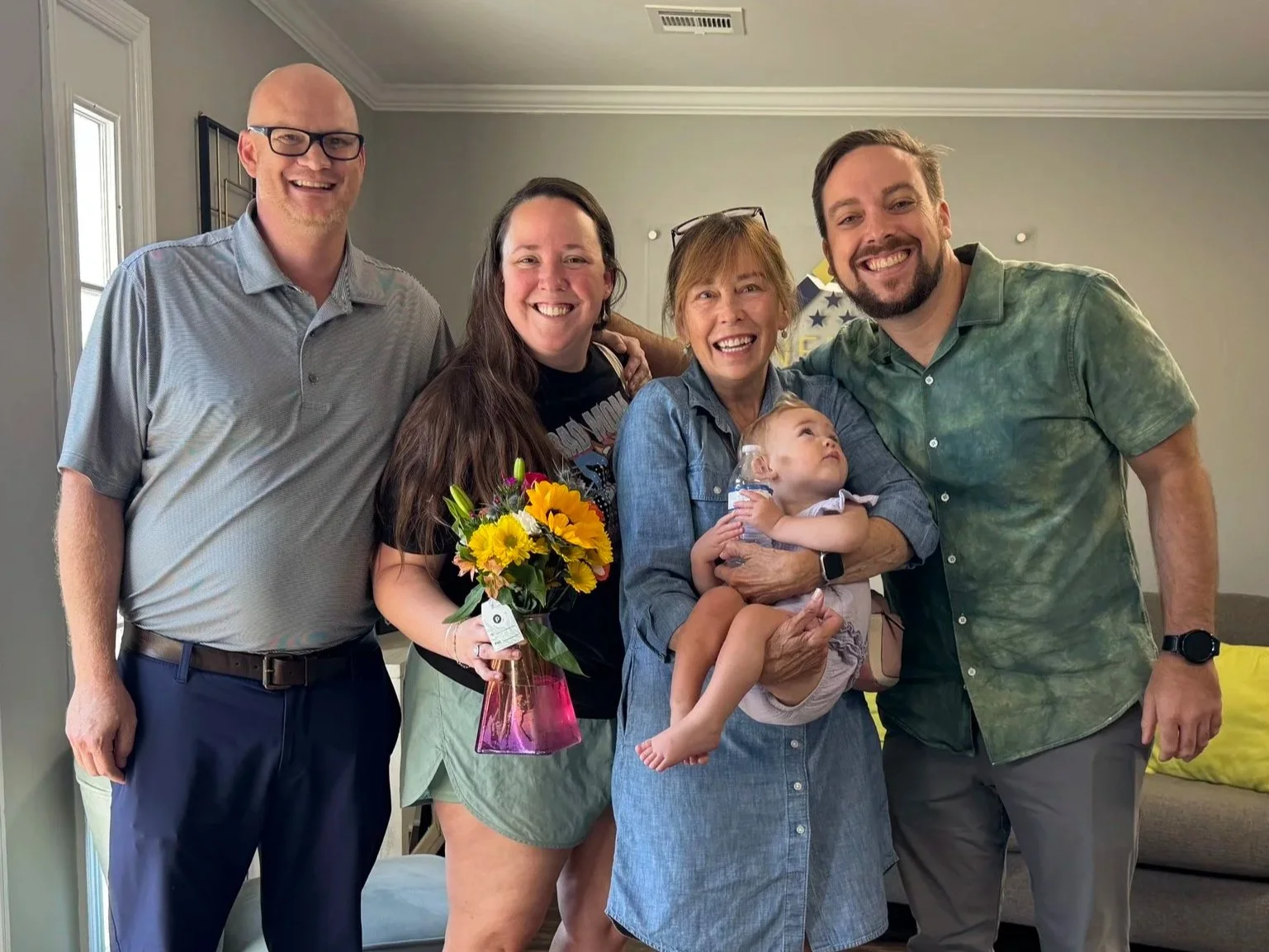 Corey and a family of four holding flowers and a baby, celebrating their home purchase