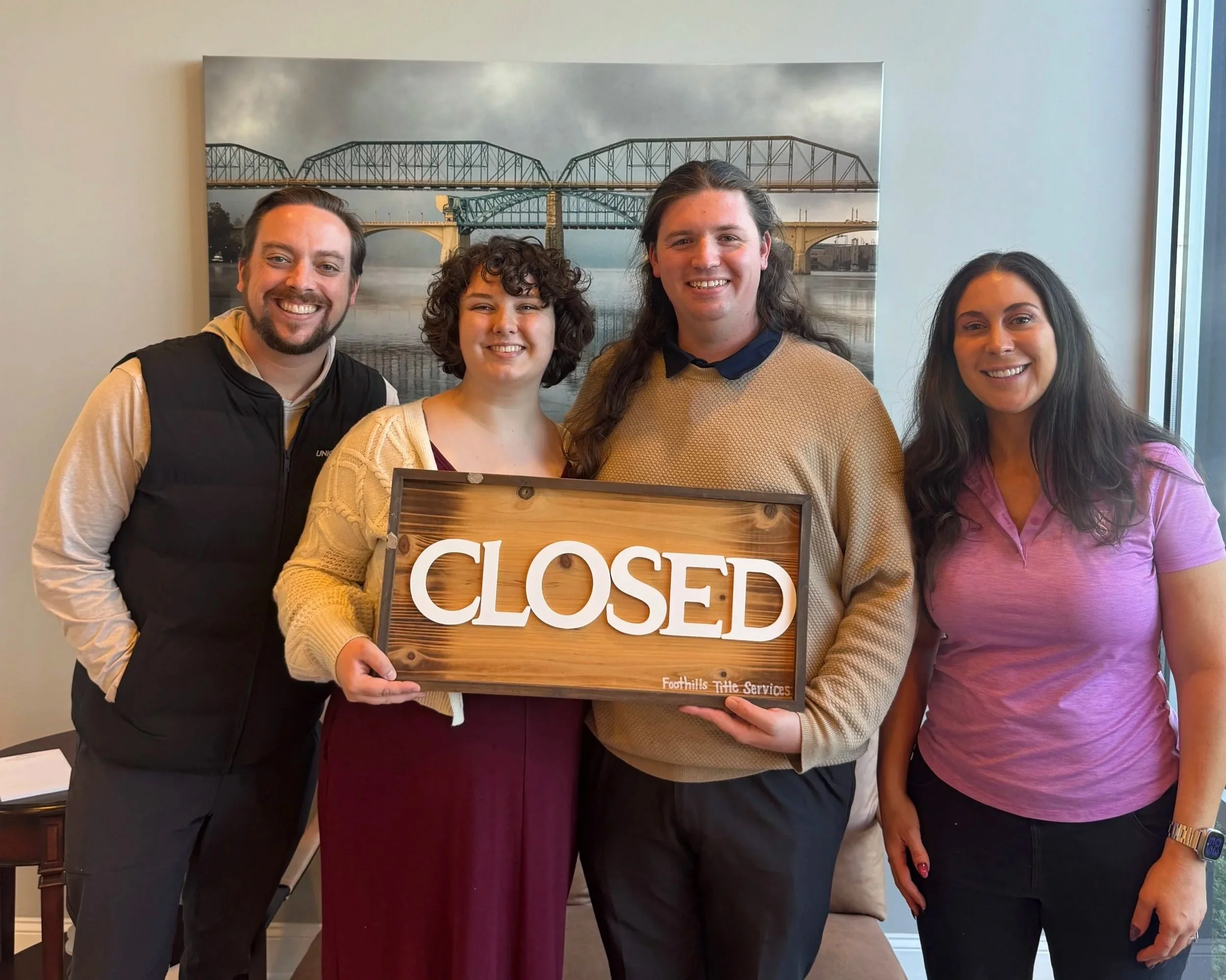 Corey celebrating a home purchase with a couple holding a "closed" sign.
