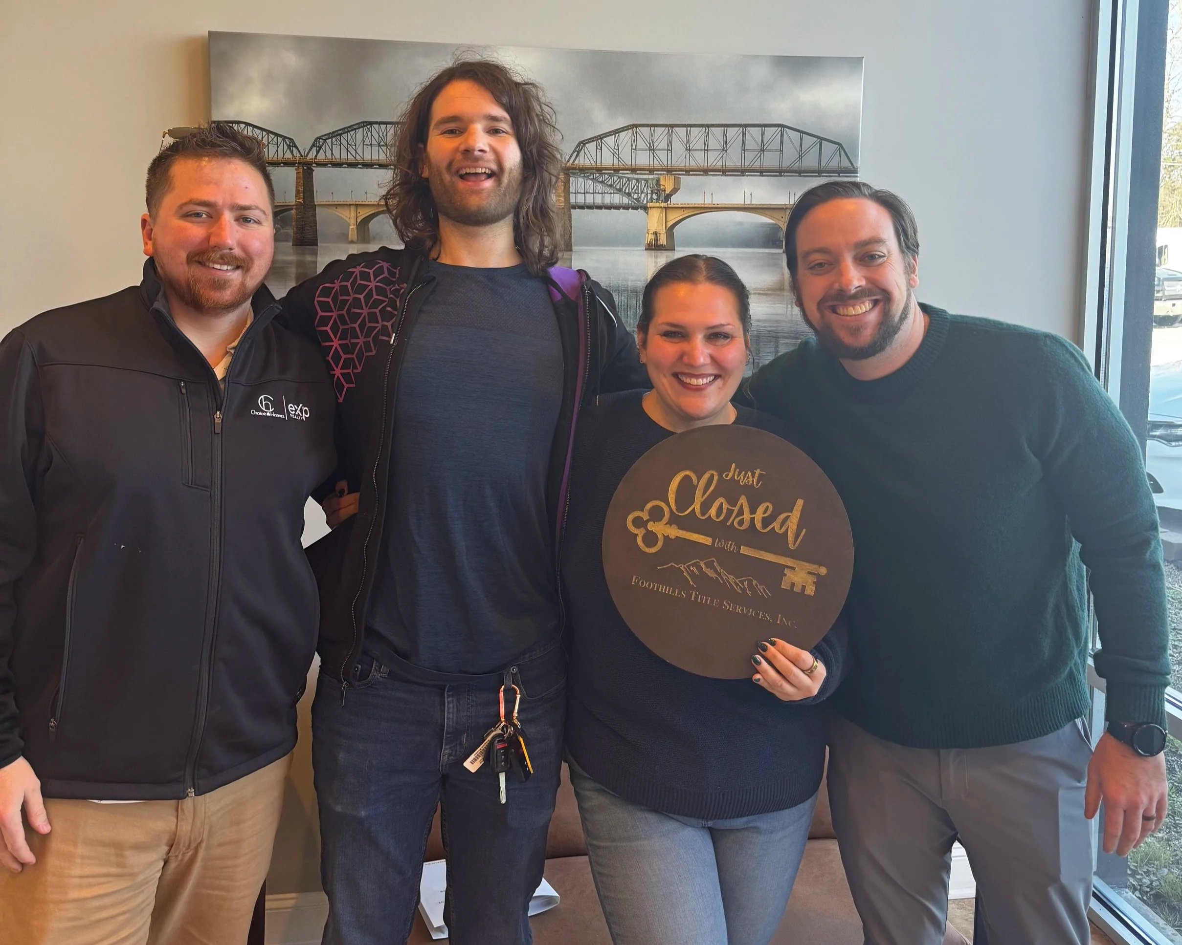 Corey celebrating a home purchase with clients holding a "Just Closed" sign