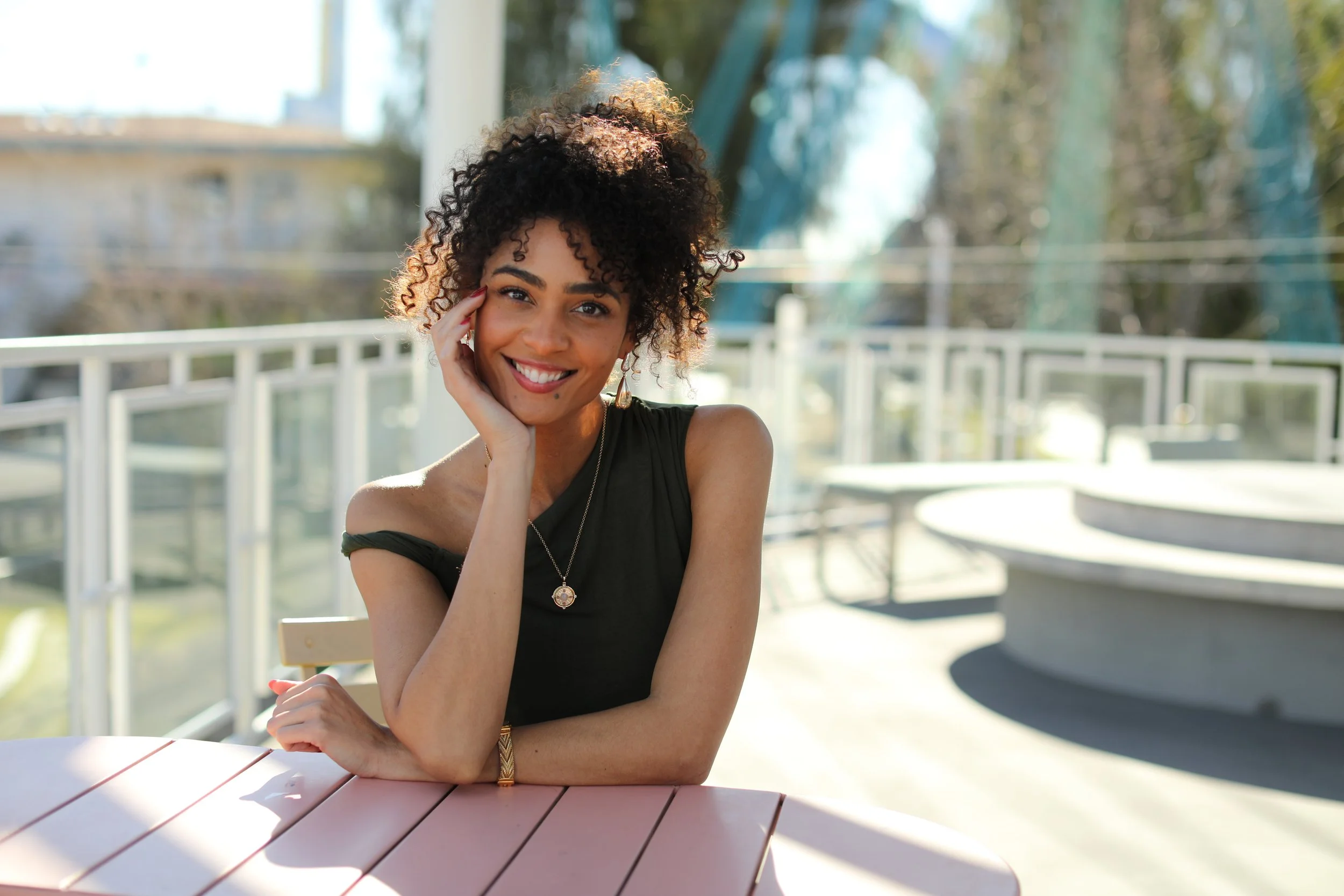Portrait of woman posing for a portrait at a table outdoors.