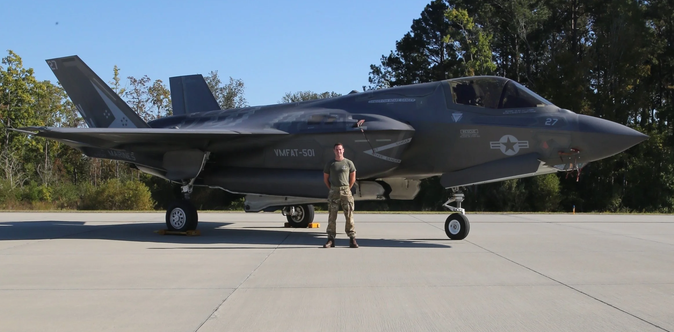 Soldier standing in front of a US fighter jet.