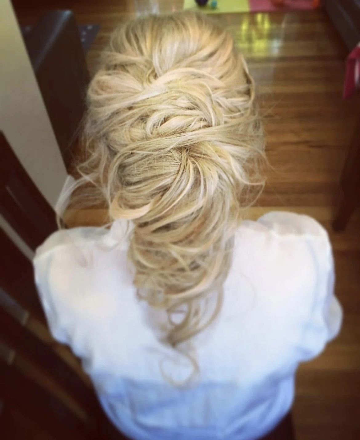 Blonde woman's hair styled in loose, flowing curls seen from above.