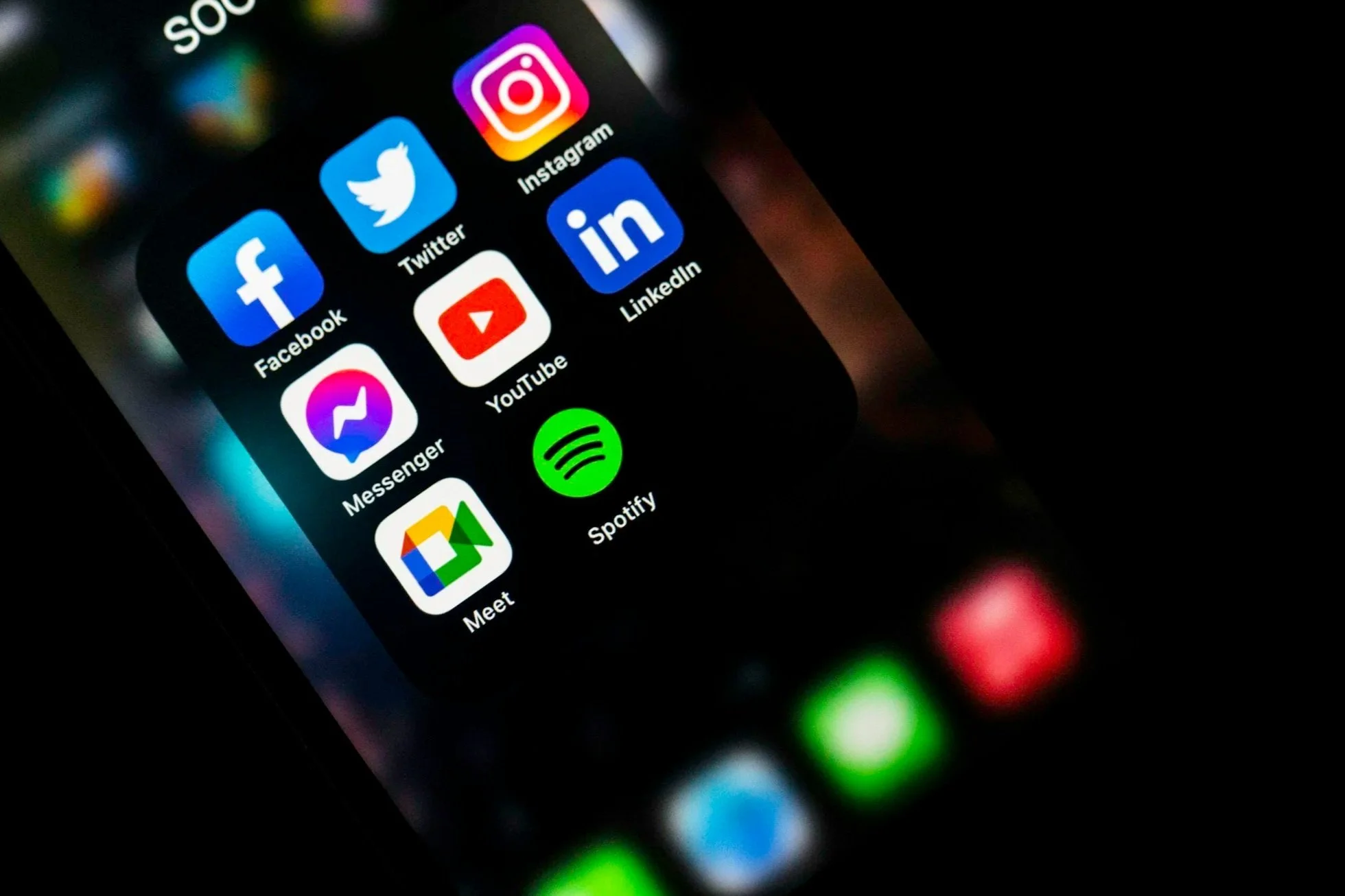 Smartphone screen displaying app icons for Facebook, Messenger, Twitter, YouTube, LinkedIn, Instagram, Spotify, and Meet.