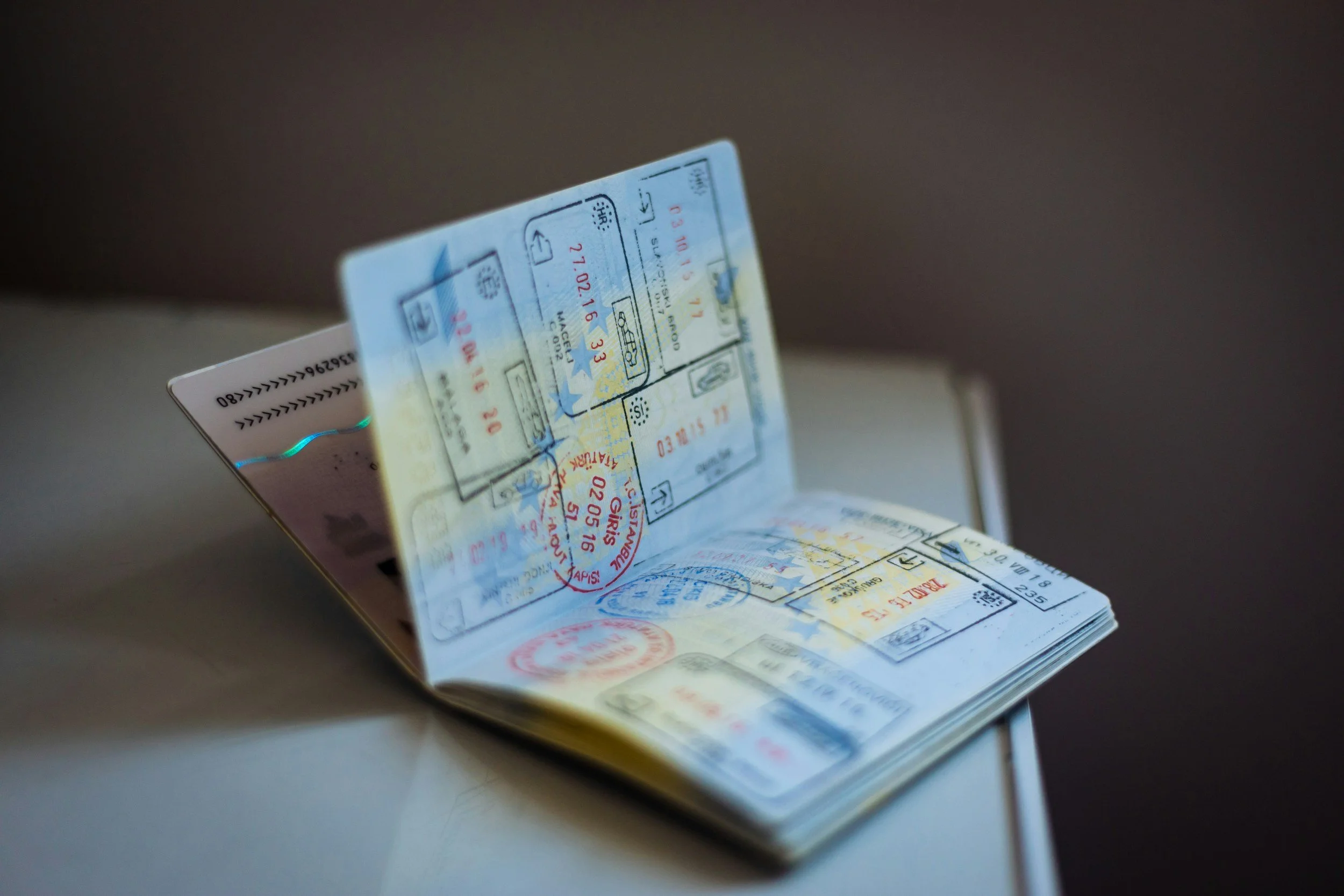 Open passport or travel document with multiple stamps inside, resting on a surface.