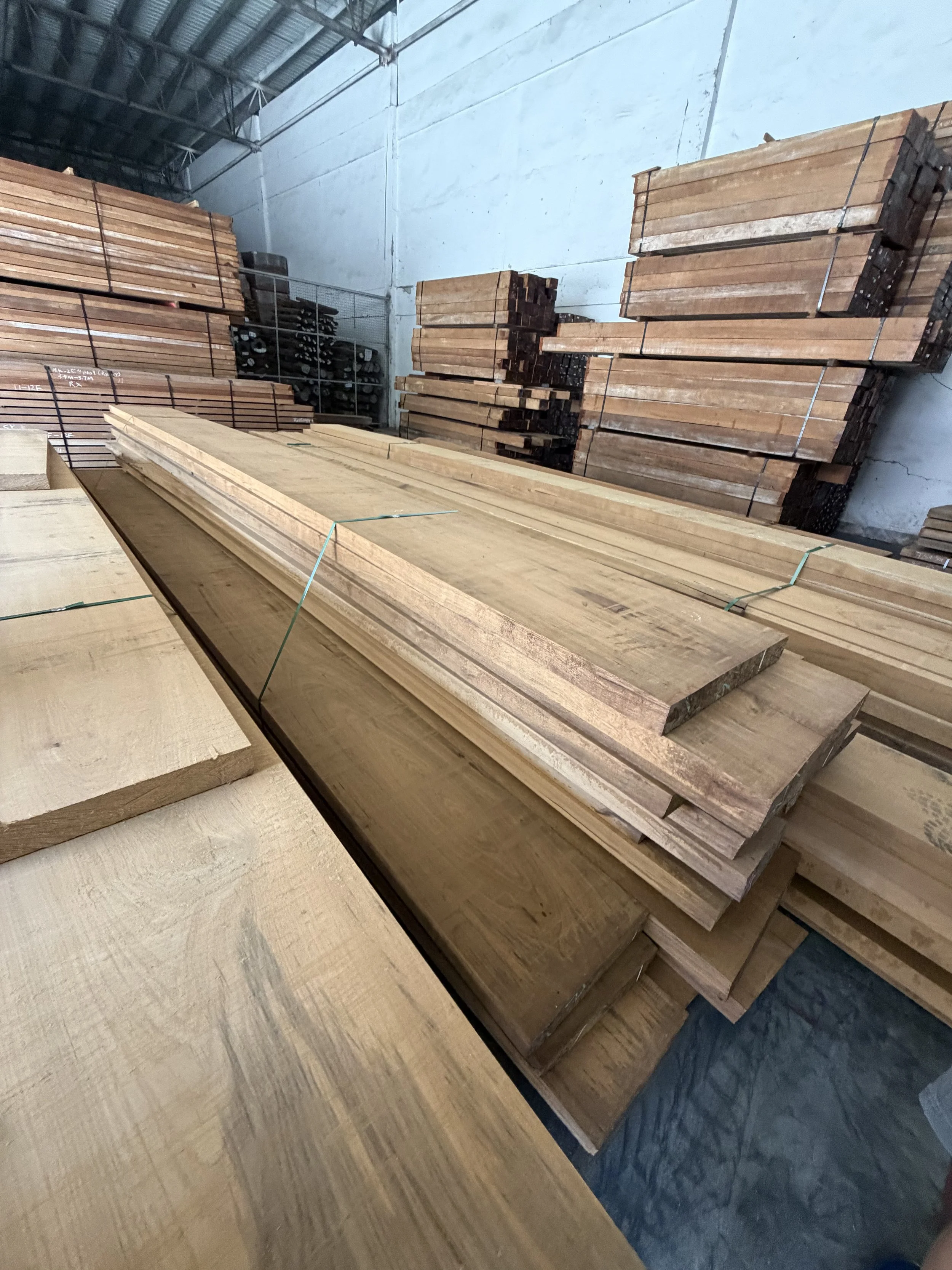 Stacks of lumber in a warehouse with wooden boards and framing materials organized on shelves and the floor.