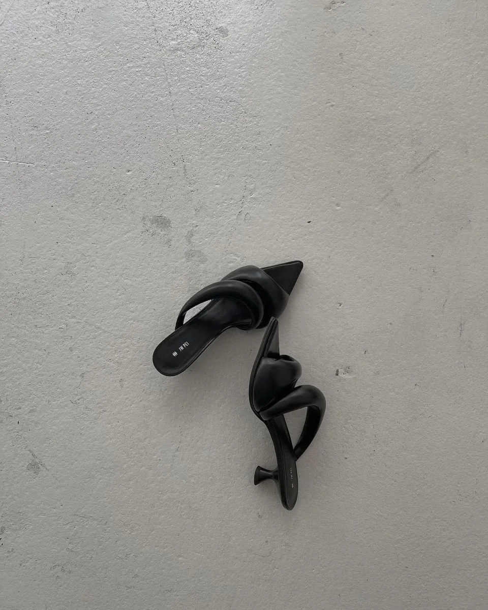 Black plastic hooks hanging on a white textured ceiling.