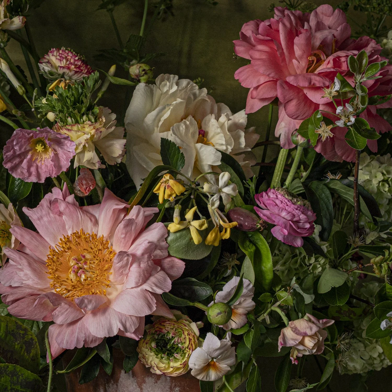 A colorful bouquet of various flowers including peonies, roses, and other blossoms in shades of pink, white, yellow, and cream with green foliage.